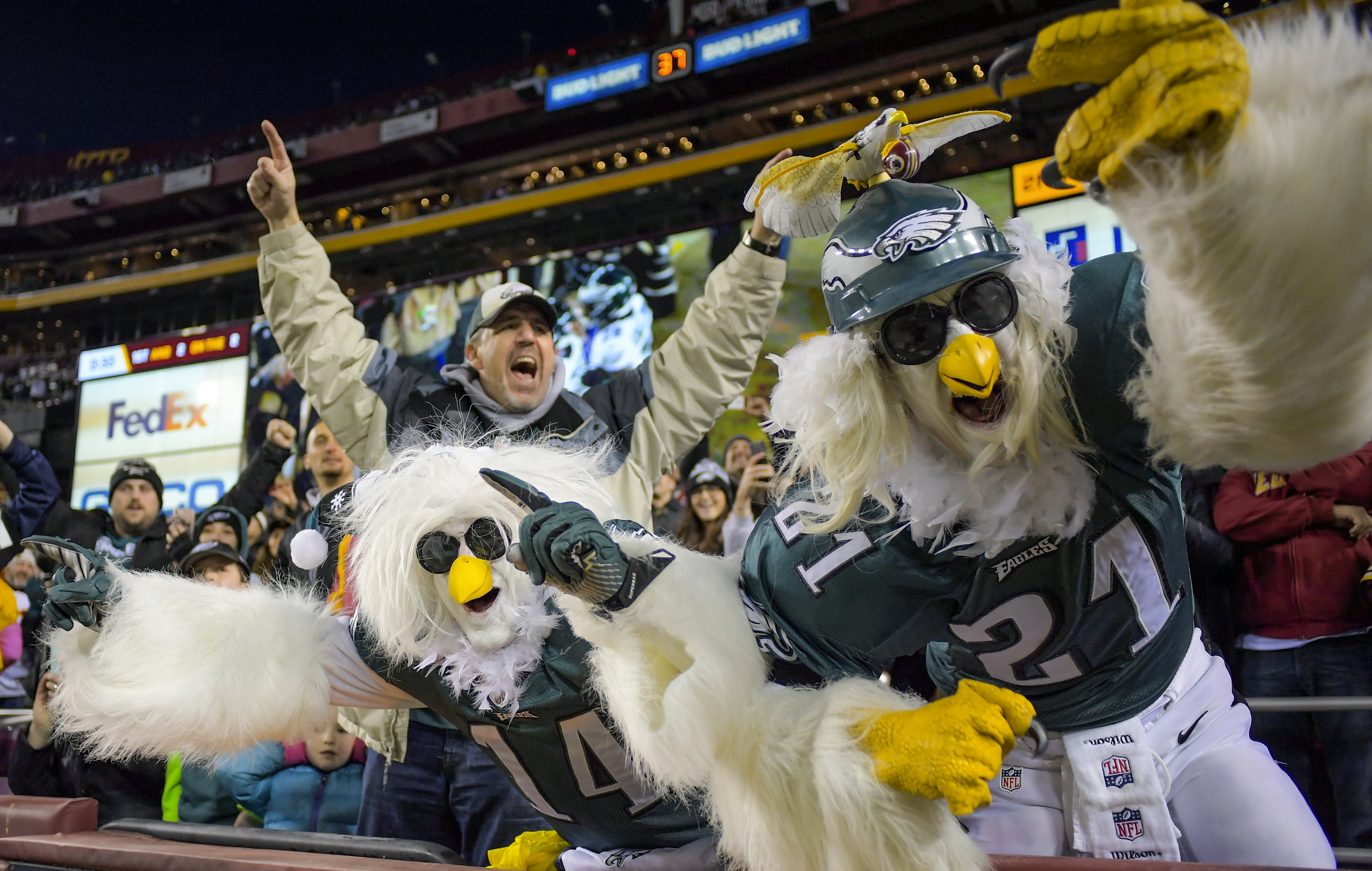 A pair of people dressed up as eagles stand up and cheering during and NFL game between the Philadelphia Eagles and Washington Redskins; nfl cities travel