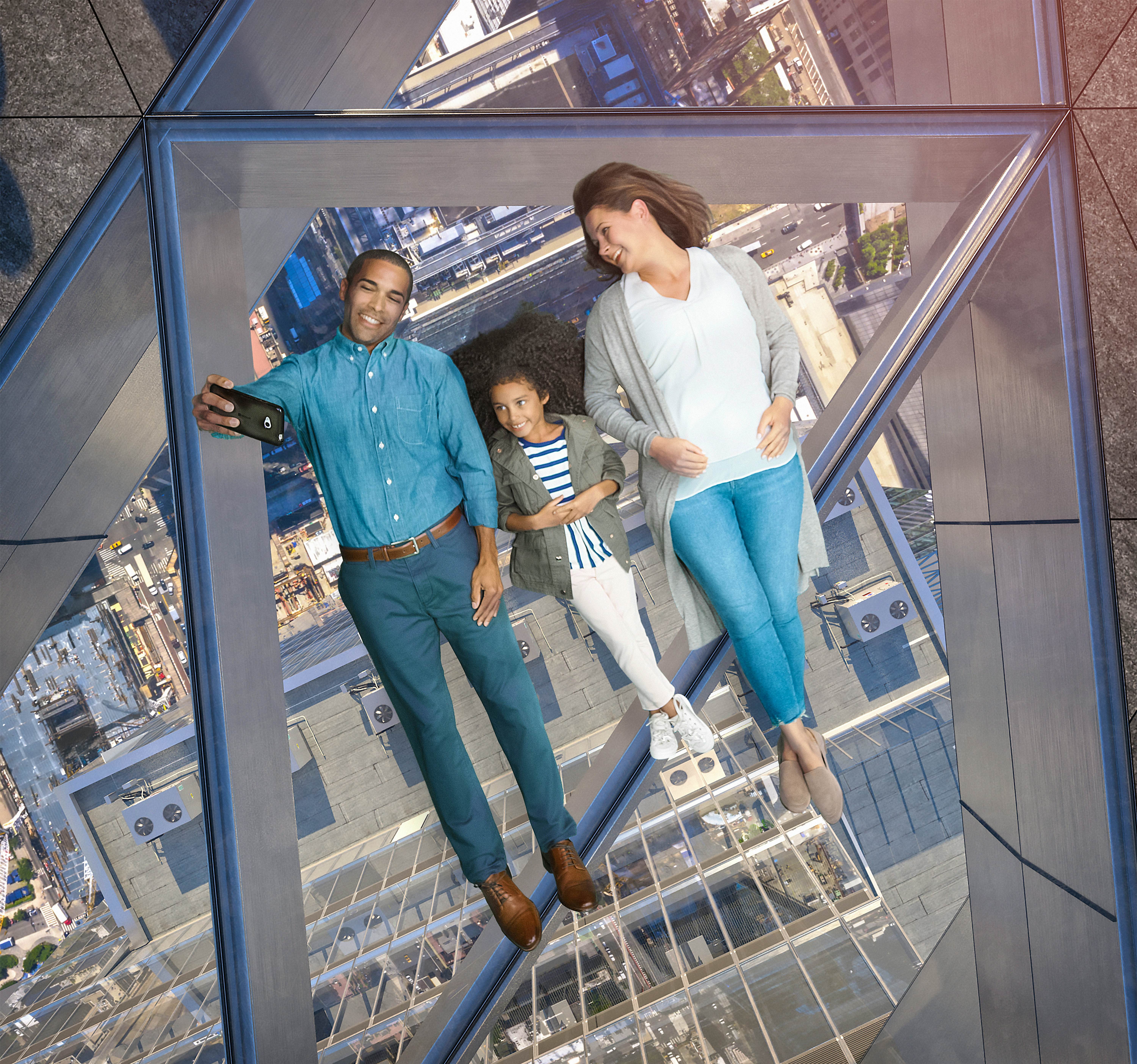 Família deitar de barriga para cima em um piso de vidro acima de Nova York