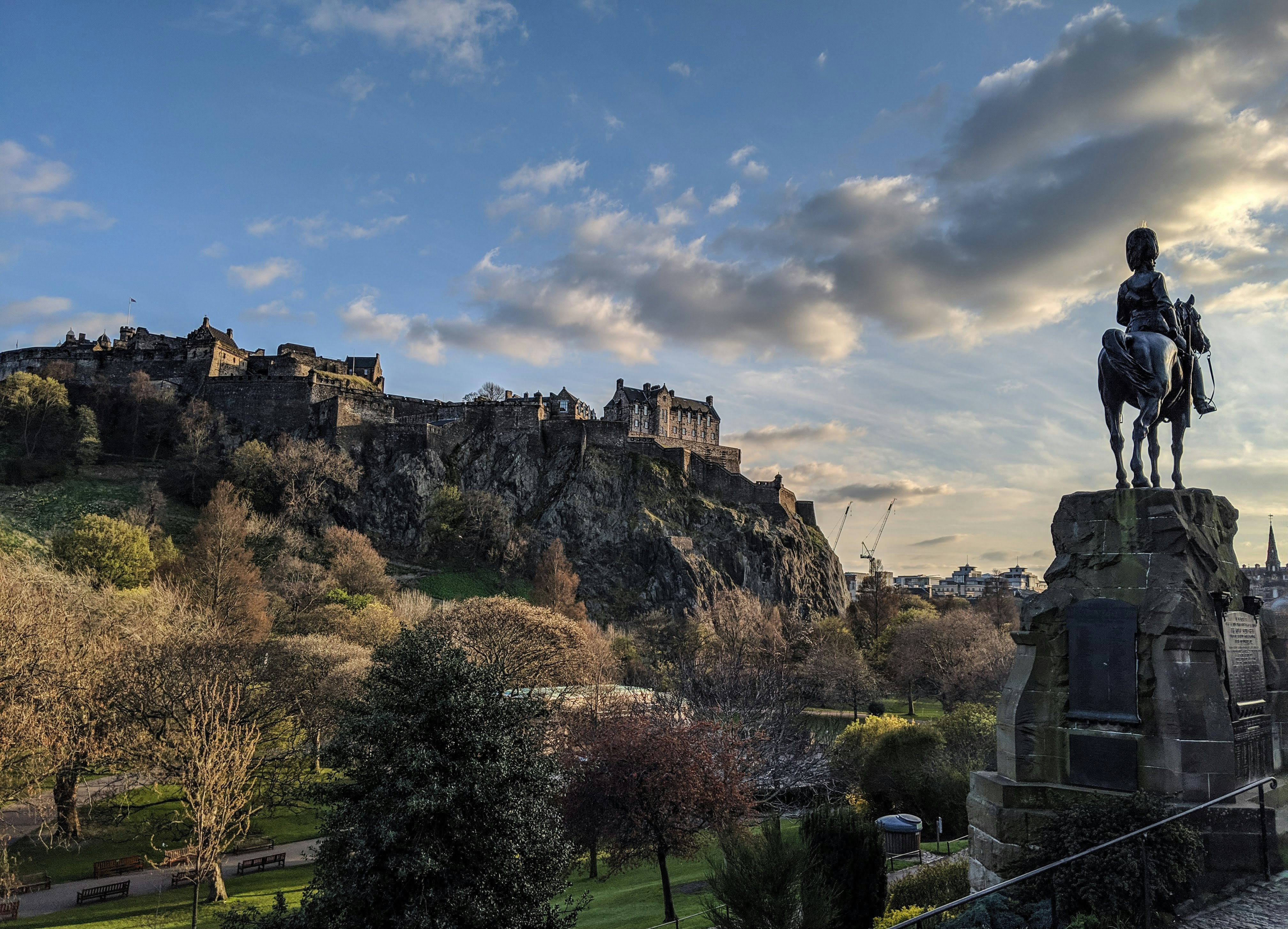 A wide view of Edinburgh with the castle in the background and a statue of a man on horseback in the foreground