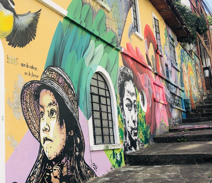 The side of a building is painted with beautiful images of young women and colorful birds