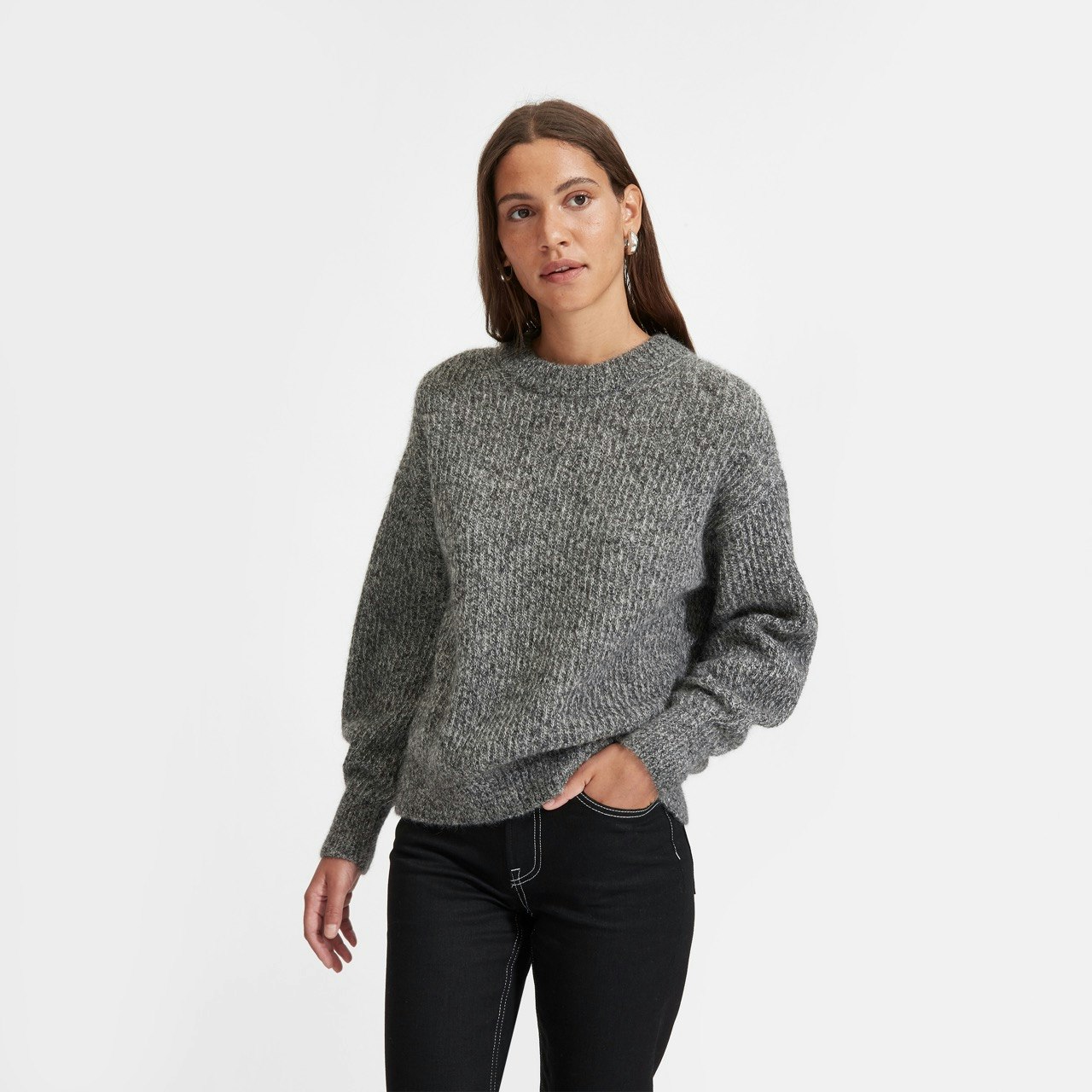 a model wearing Everlane's oversized alpaca crewneck sweater in charcoal twist, with black pants