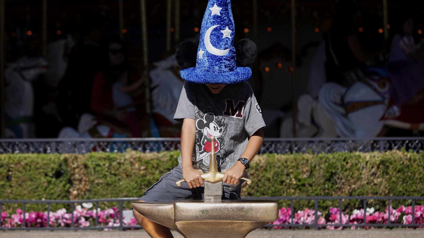 A boy pulls on the Sword in the Stone in front of the King Arthur Carrousel at Walt Disney Co.'s Disneyland Park, part of the Disneyland Resort, in Anaheim, California, U.S.