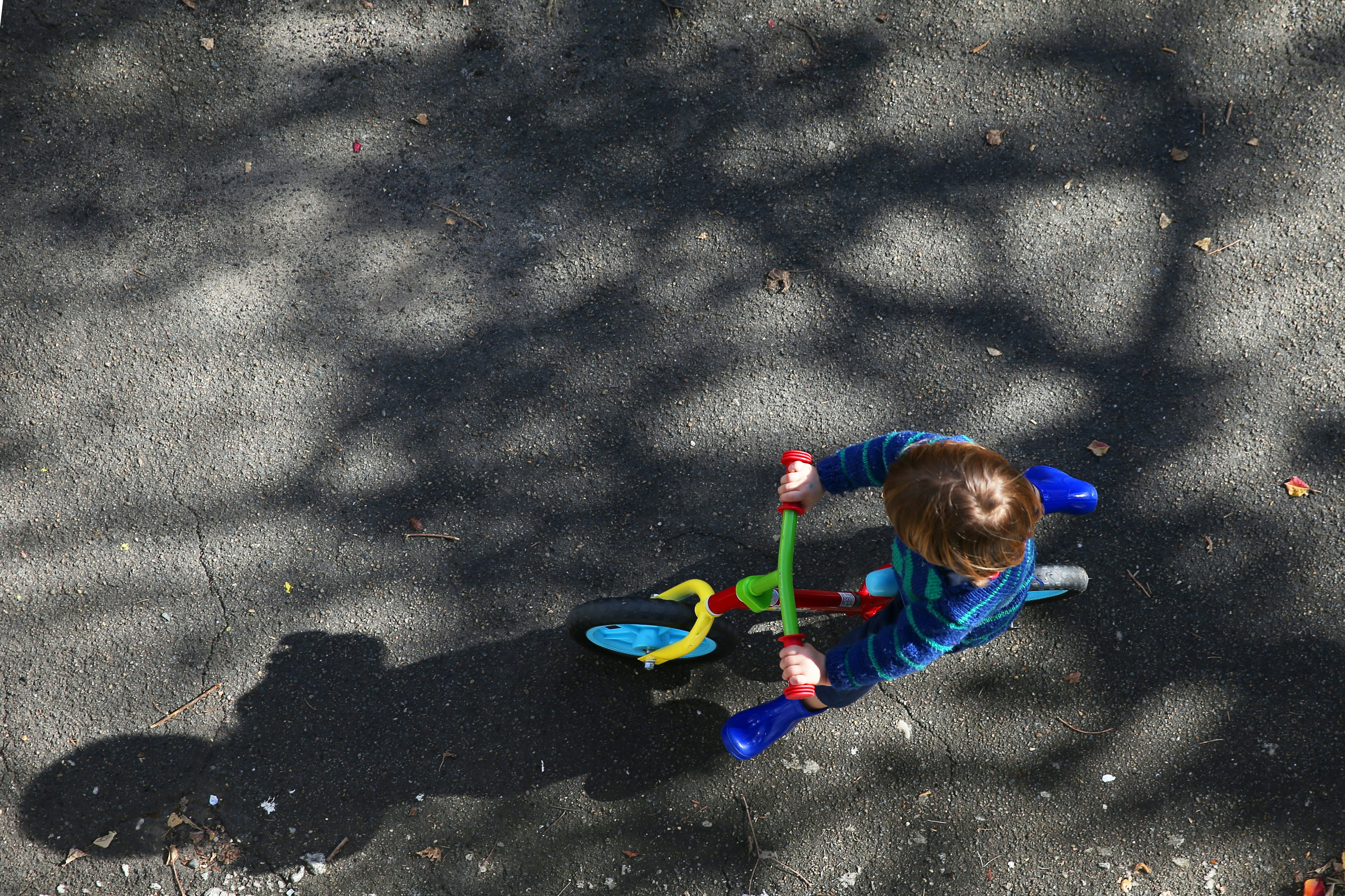 An aerial view of a child on a brightly coloured bicycle