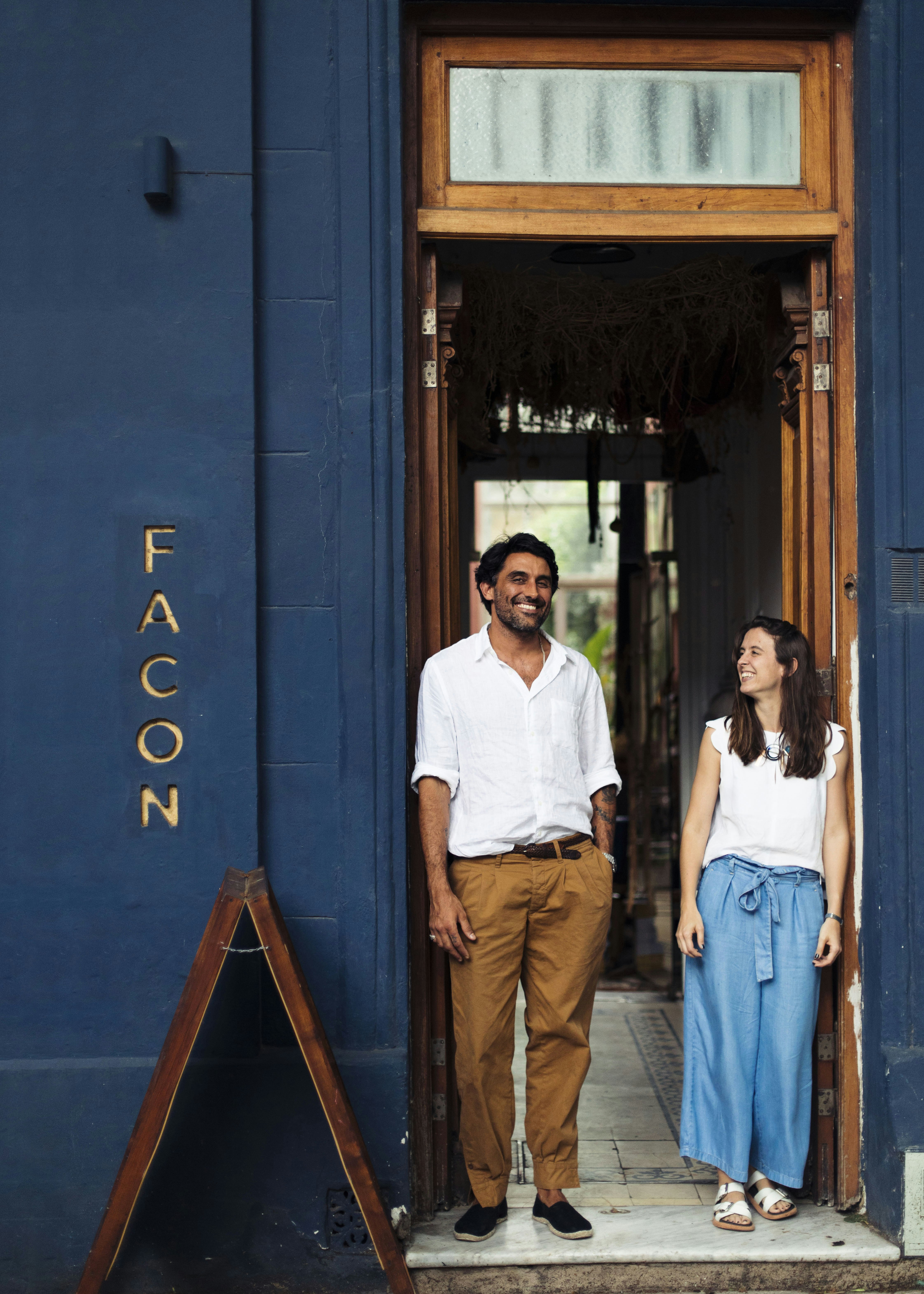 A man and woman stand in a doorway surrounded by a blue wall