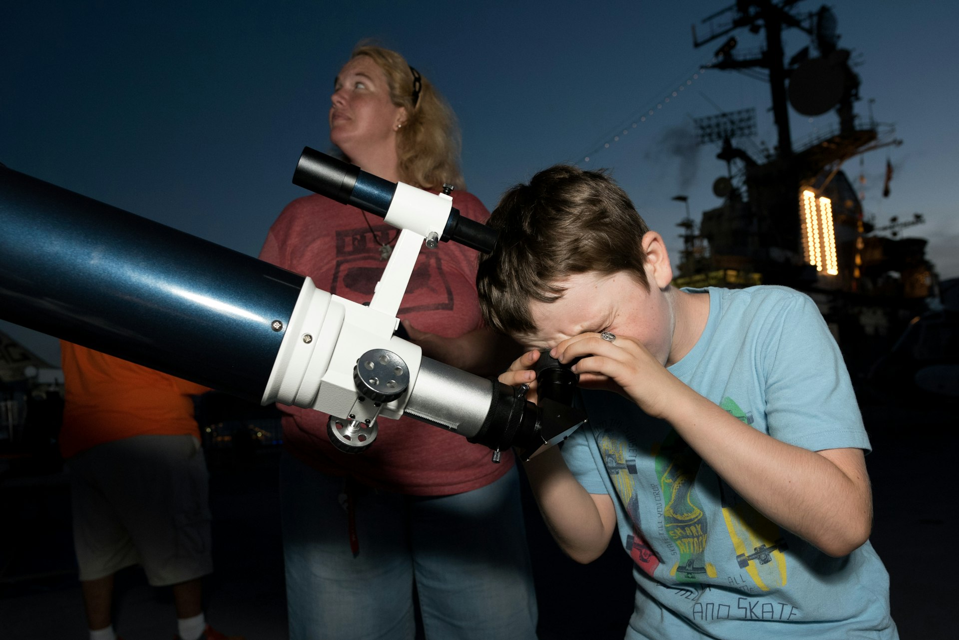 A young boy looks into a telescope