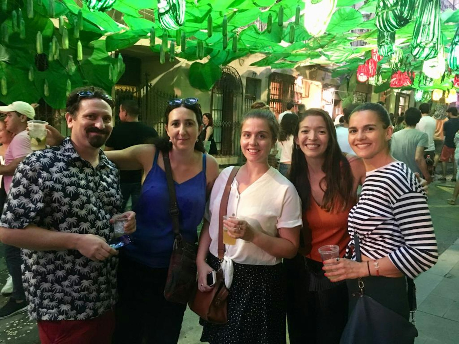 Writer Esme and four friends pose for the camera in a Barcelona street with green decorations suspended from above.