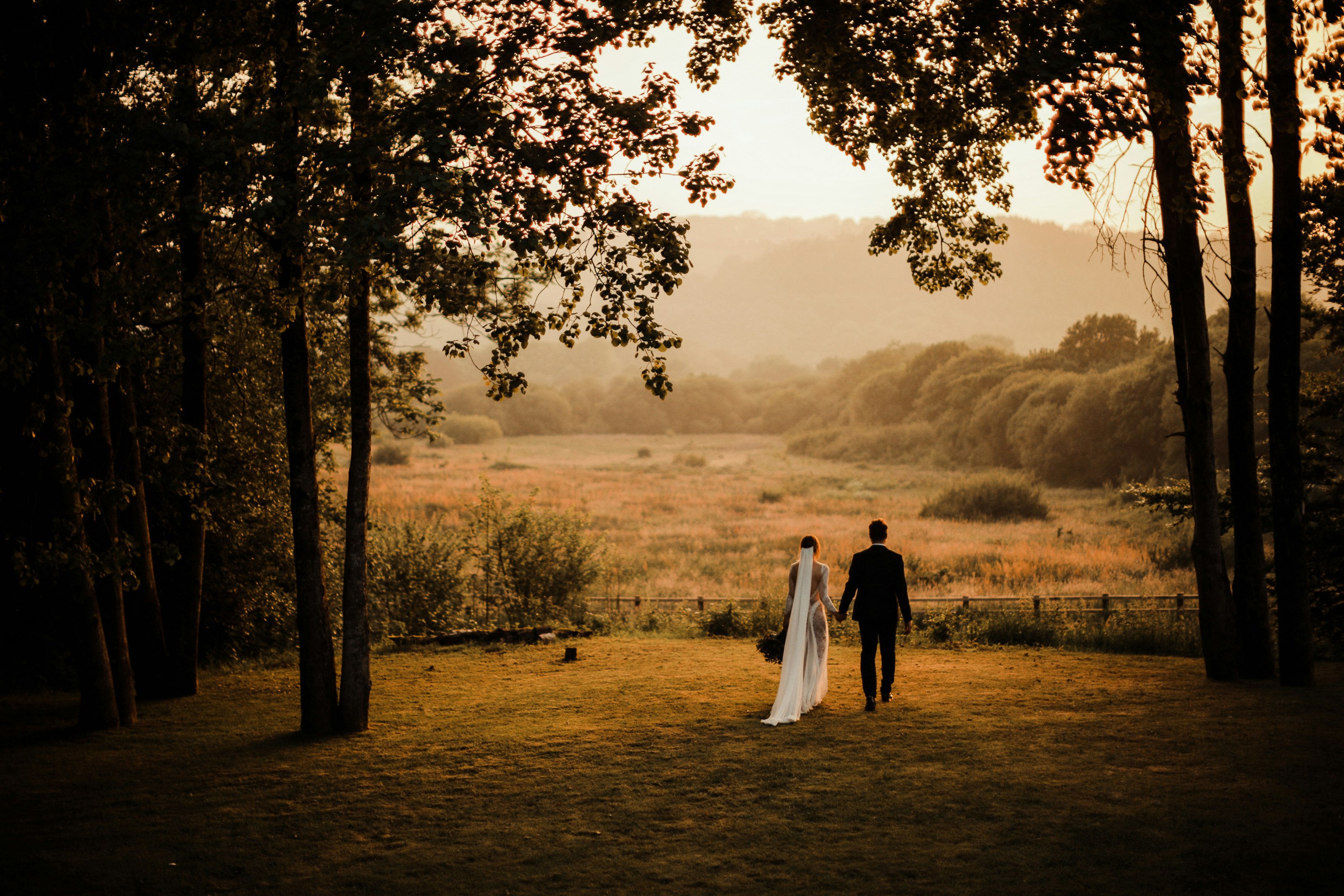 Bridal couple standing looking towards an autumnal field in Fforest Farm, Pembrokeshire