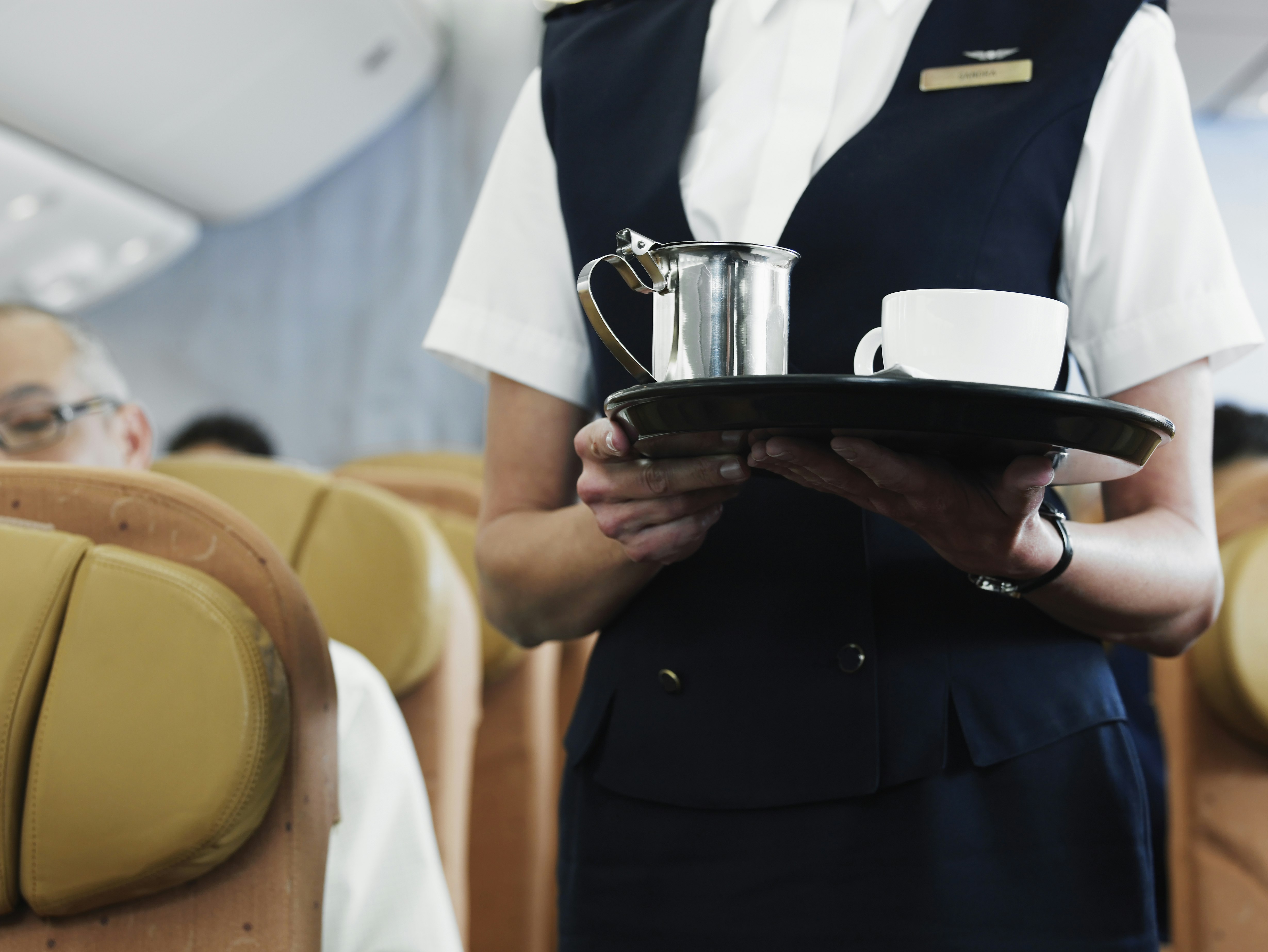 Flight attendant holding tray with coffee