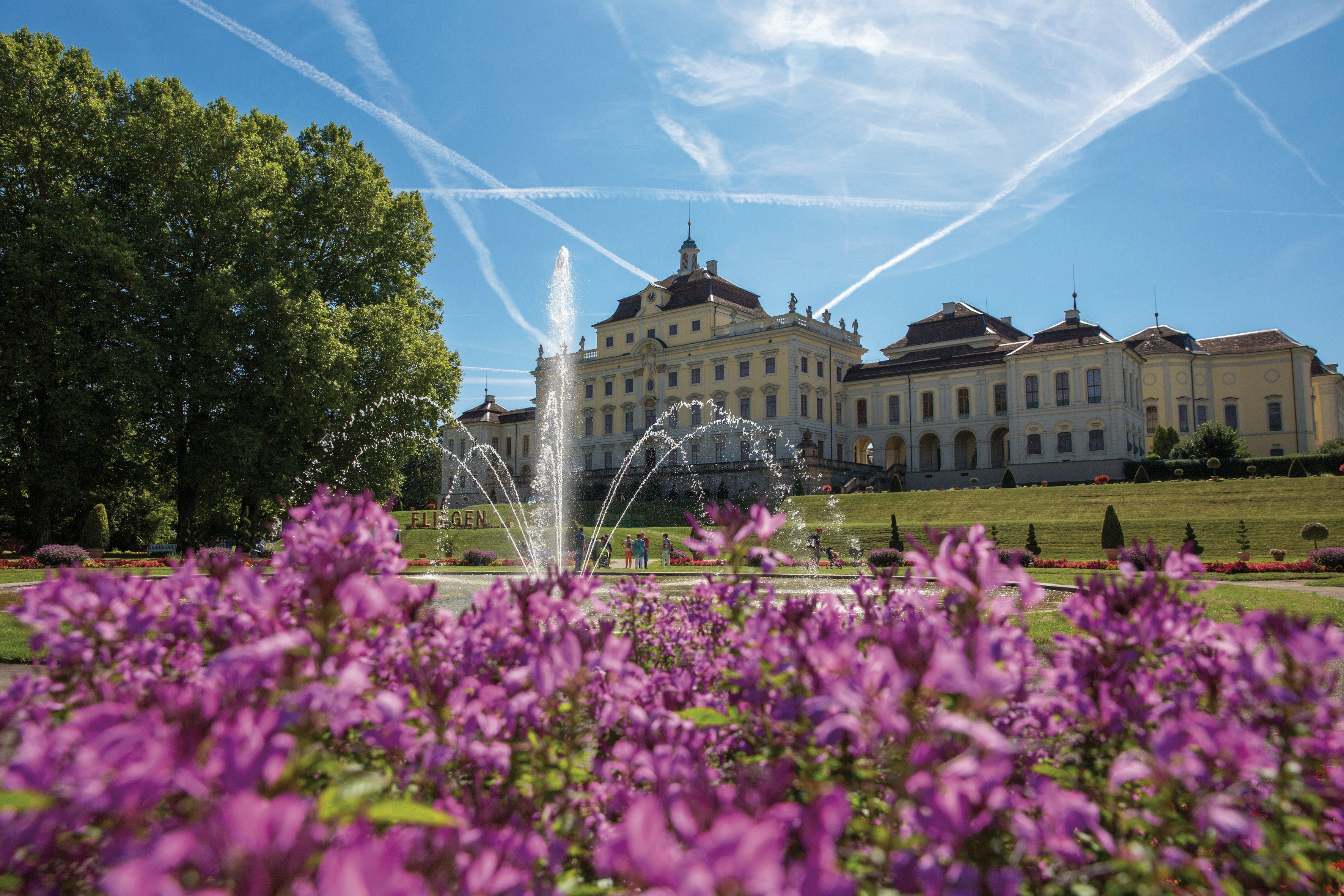 Flowers blooming outside Residenzschloss, Ludwigsburg, Germany. A fountain is visible, as are people walking in the distance.
