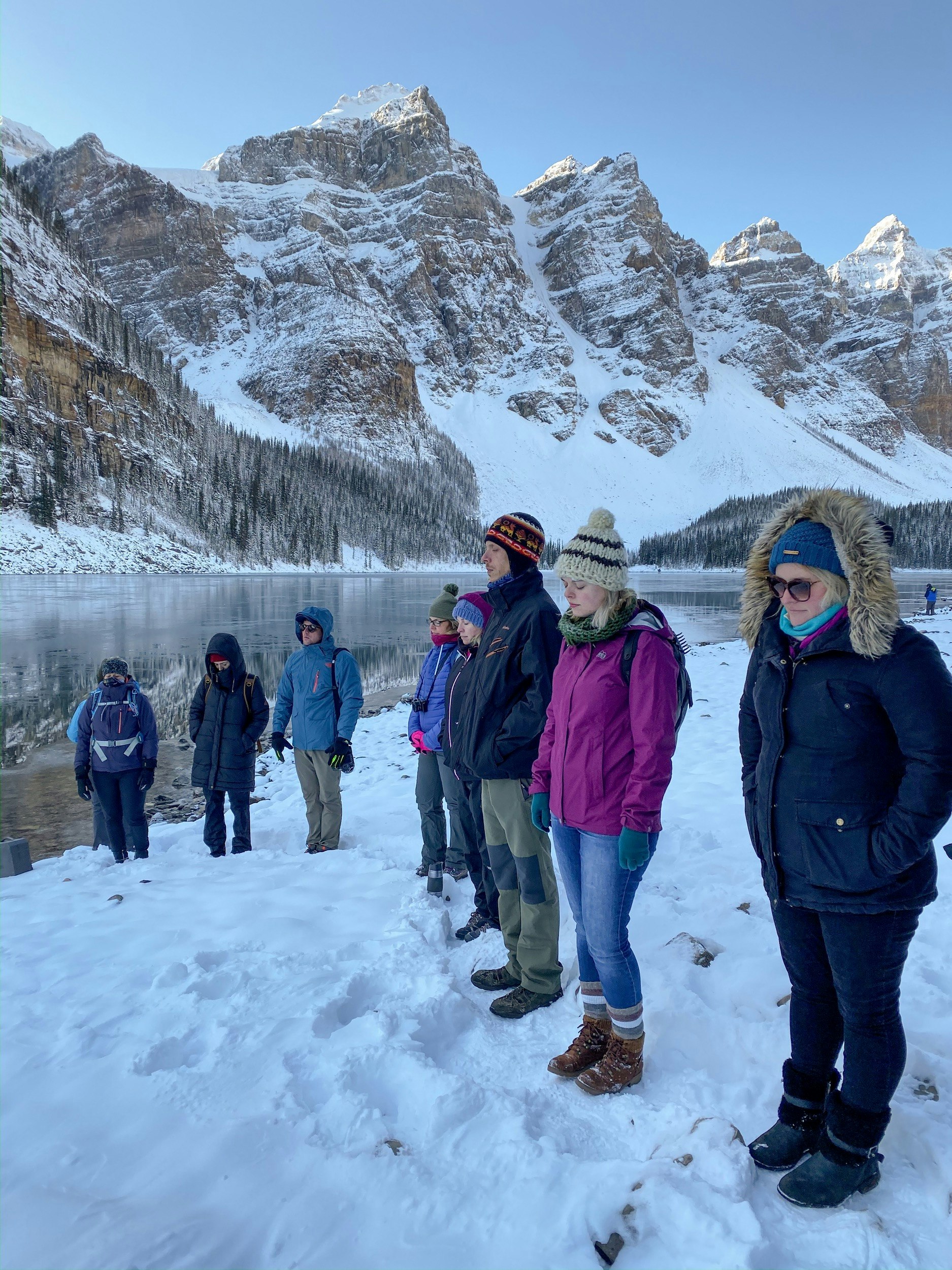 People meditate on the edge of Moraine lake in deep snow during winter at Banff and Lake Louise
