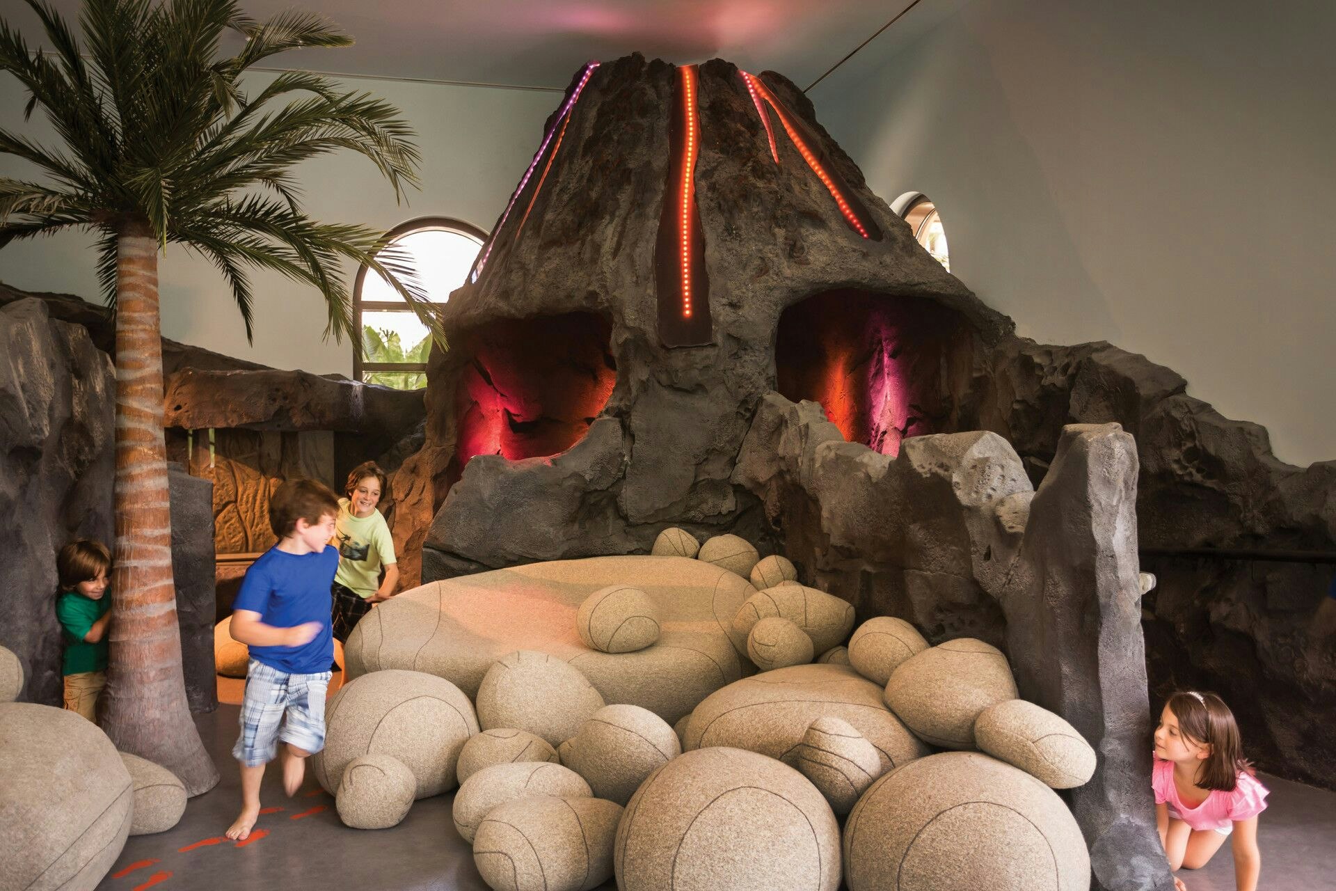 A group of children play beside a mock volcano in the play area at the Four Seasons Orlando.