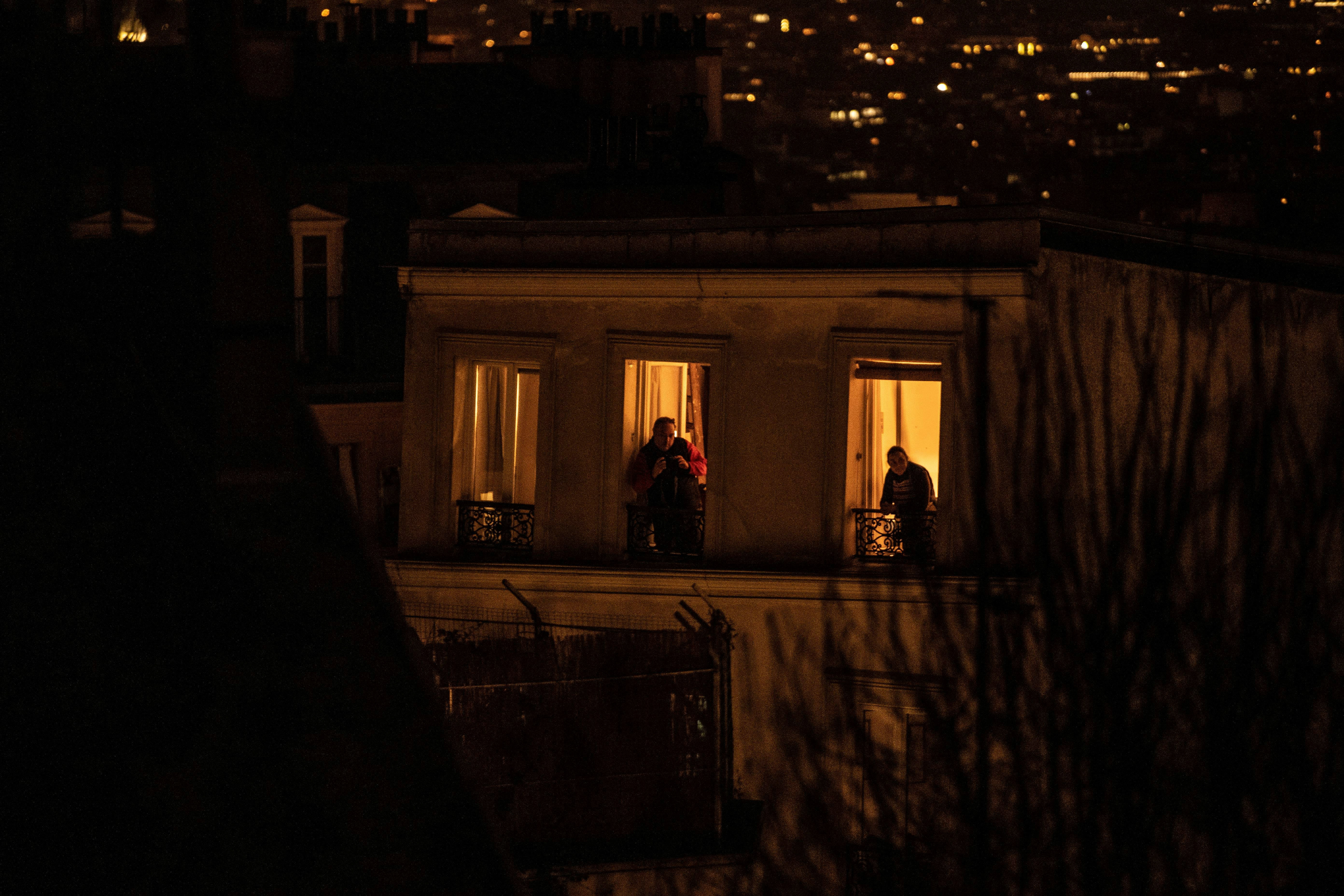 Two men look from their balconies in Paris, on March 17, 2020, as a strict lockdown comes into in effec