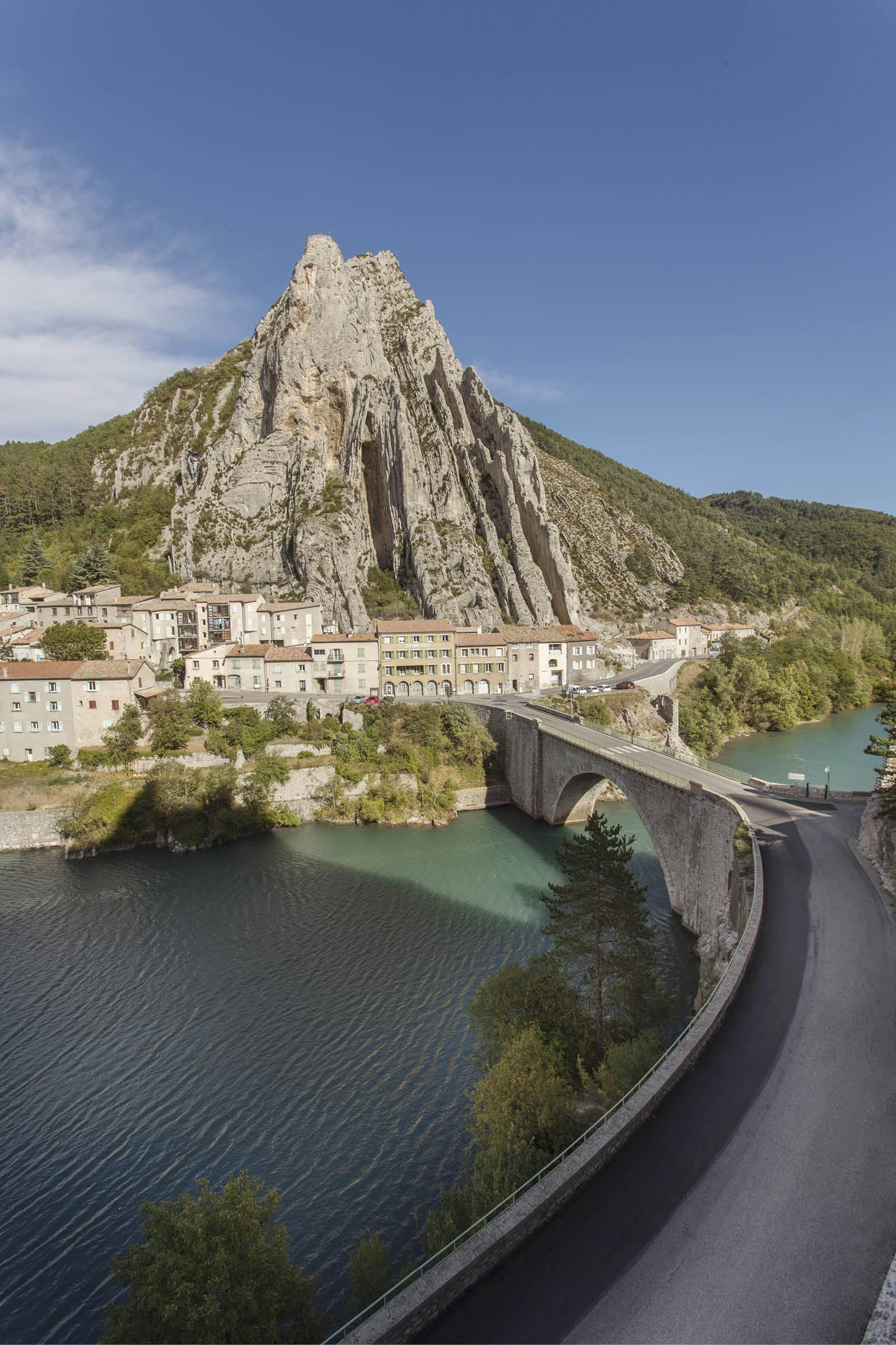 A bridge spans the Durance River at the foot of cliffs in Sisteron