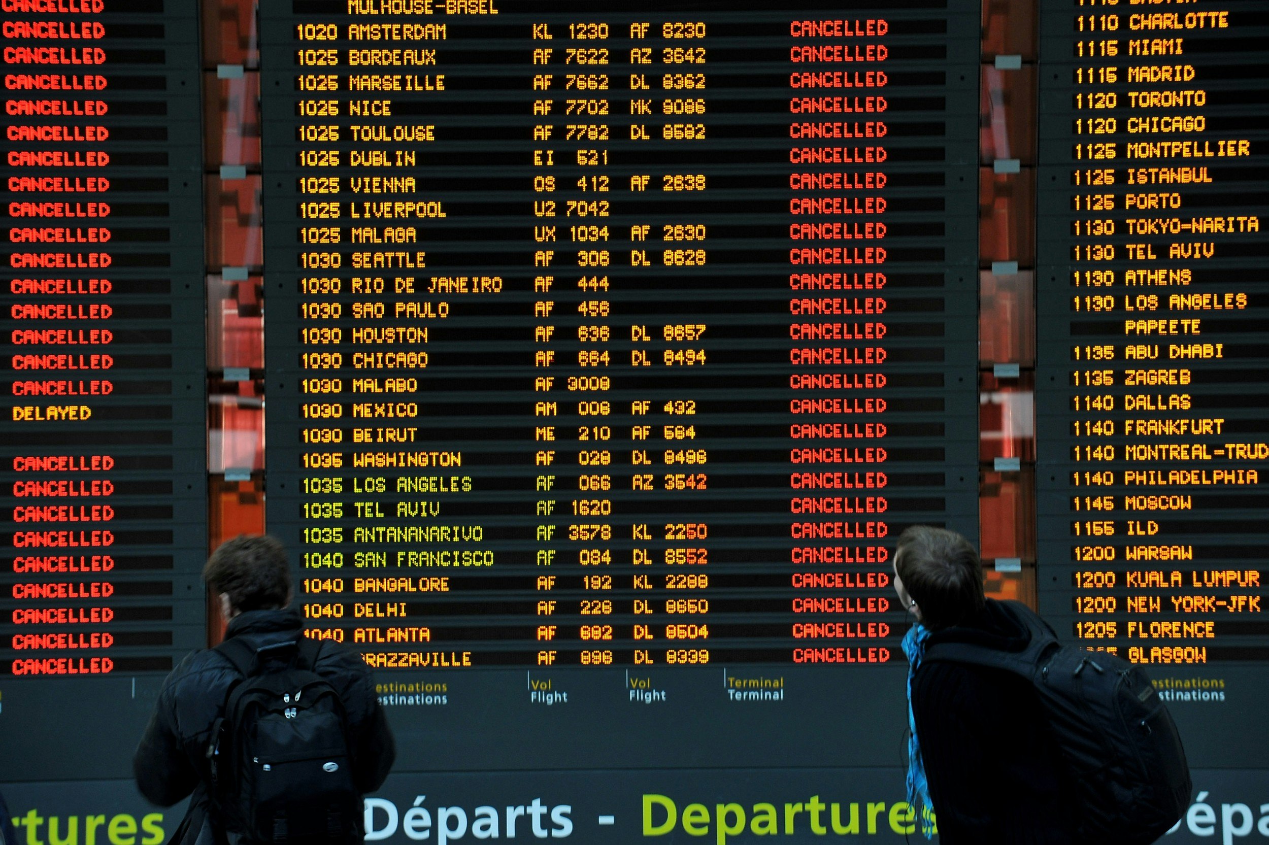 Passengers look at a flight information board that indicate cancelled flights in a terminal at the Charles-de-Gaulle airpor