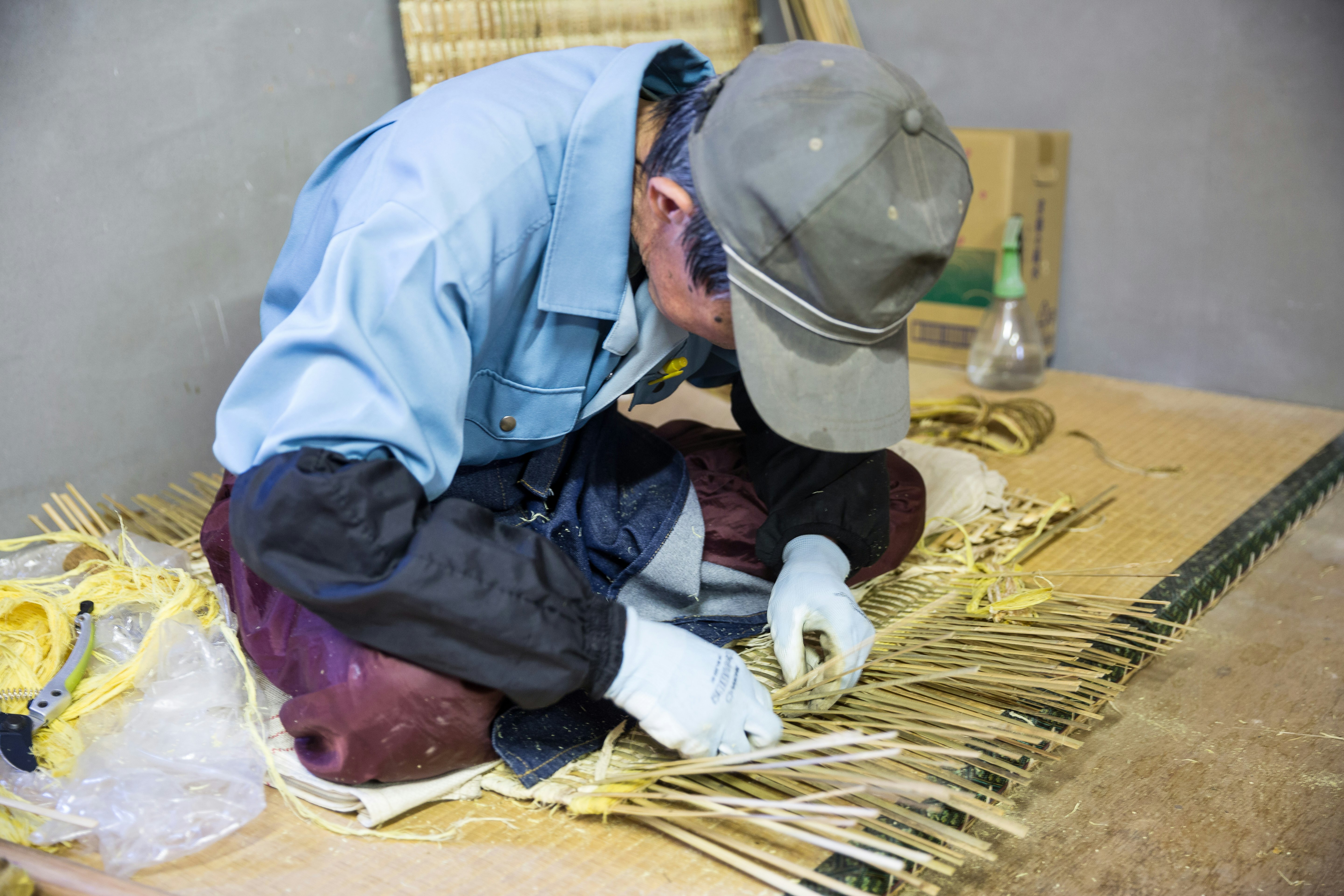 A seated artisan bends low, weaving bamboo baskets, a traditional technique that is at risk of dying out