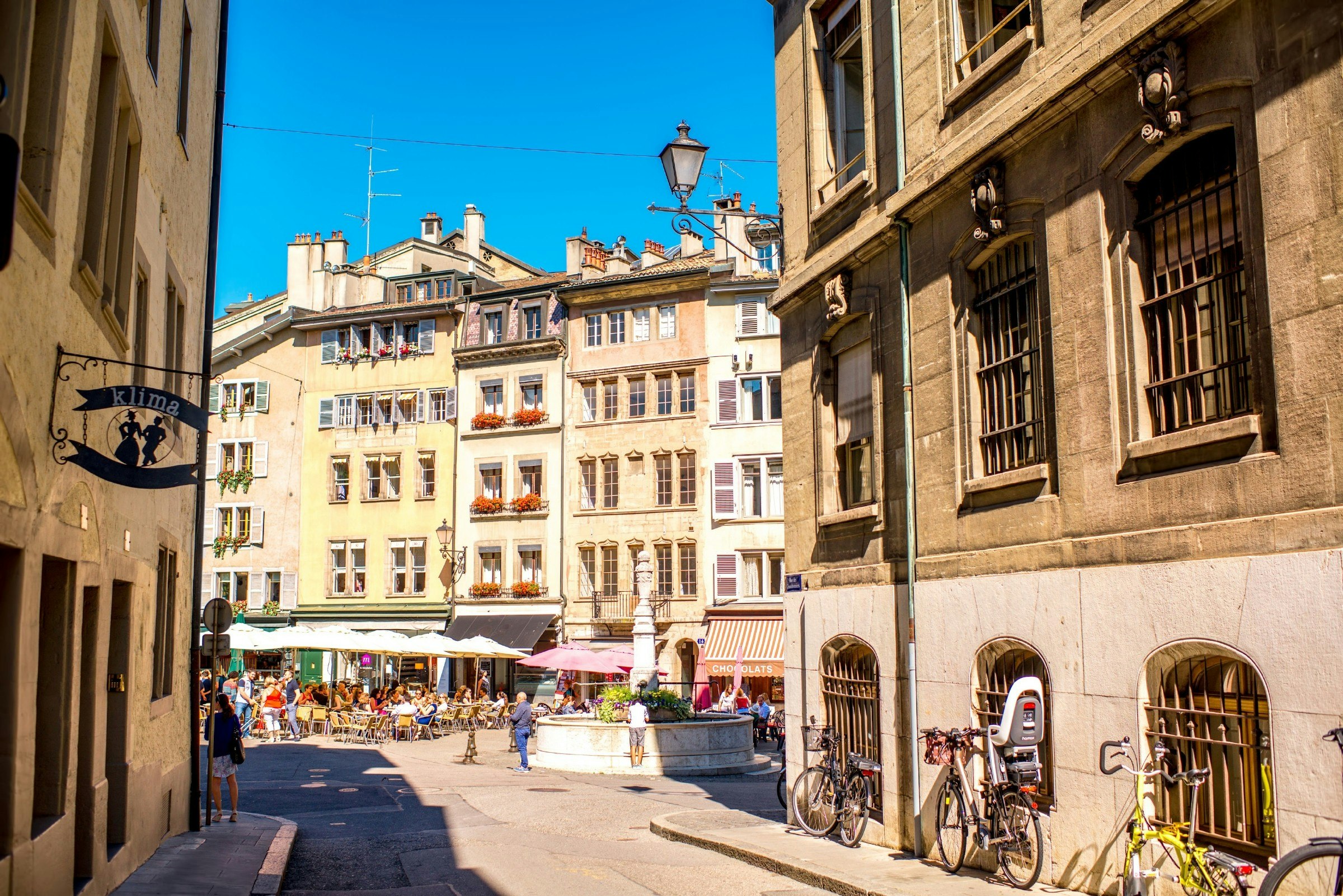 Bourg-de-four square with people seated at cafes and restaurants in Geneva