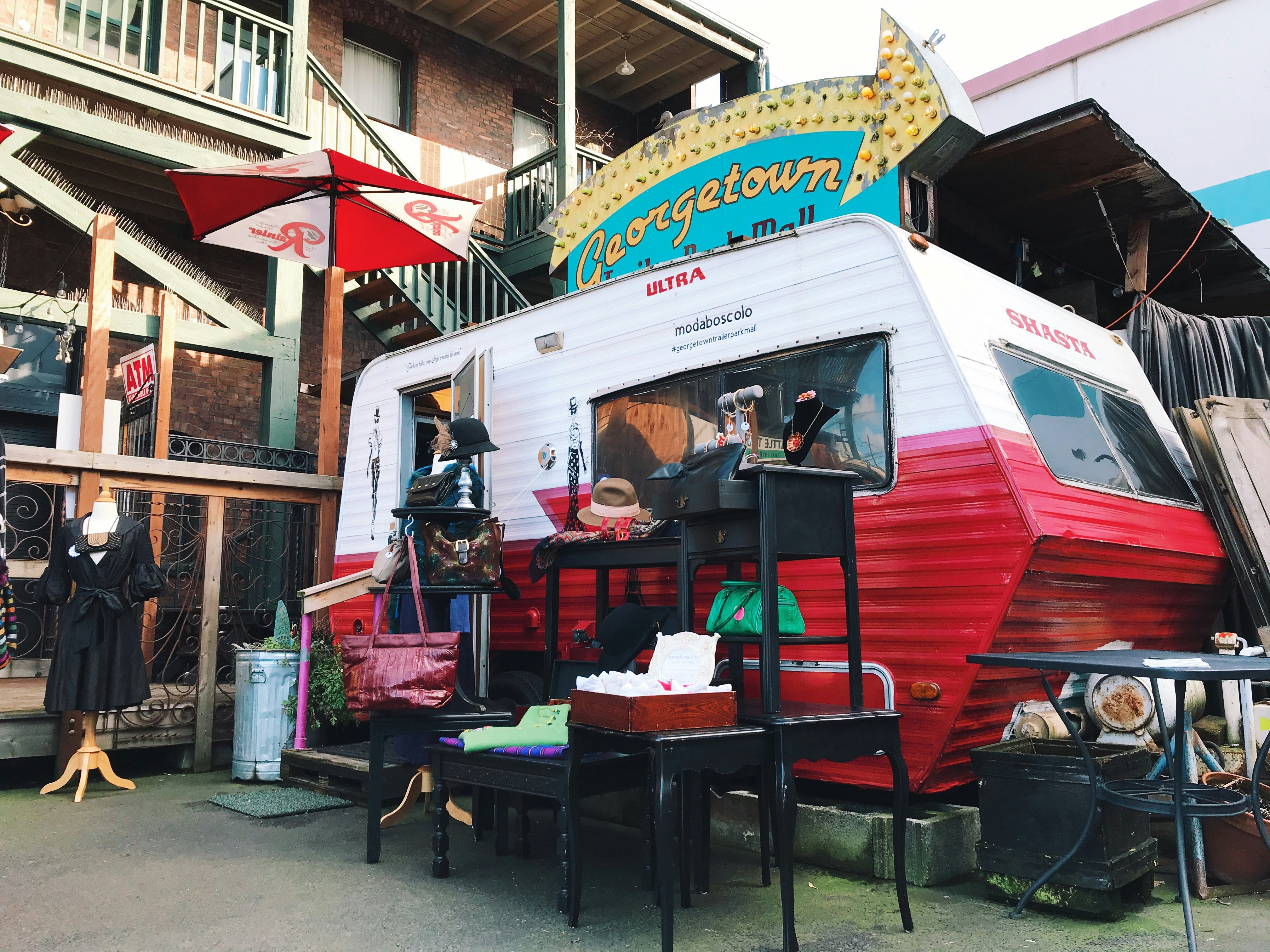 A red and white airstream trailer displays numerous racks of vintage goods