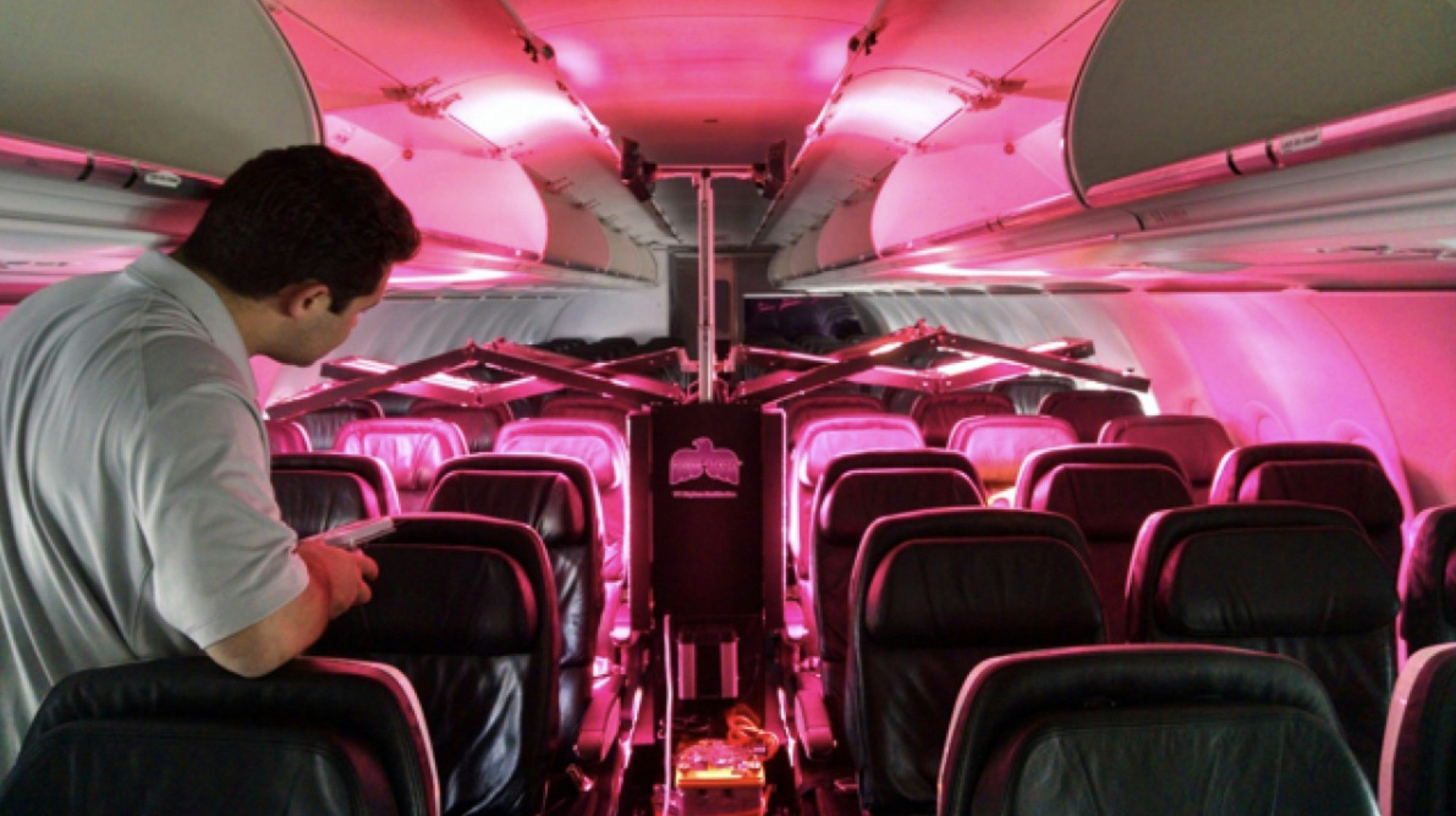 Machine emitting a pink light as it cleans a plane.jpg