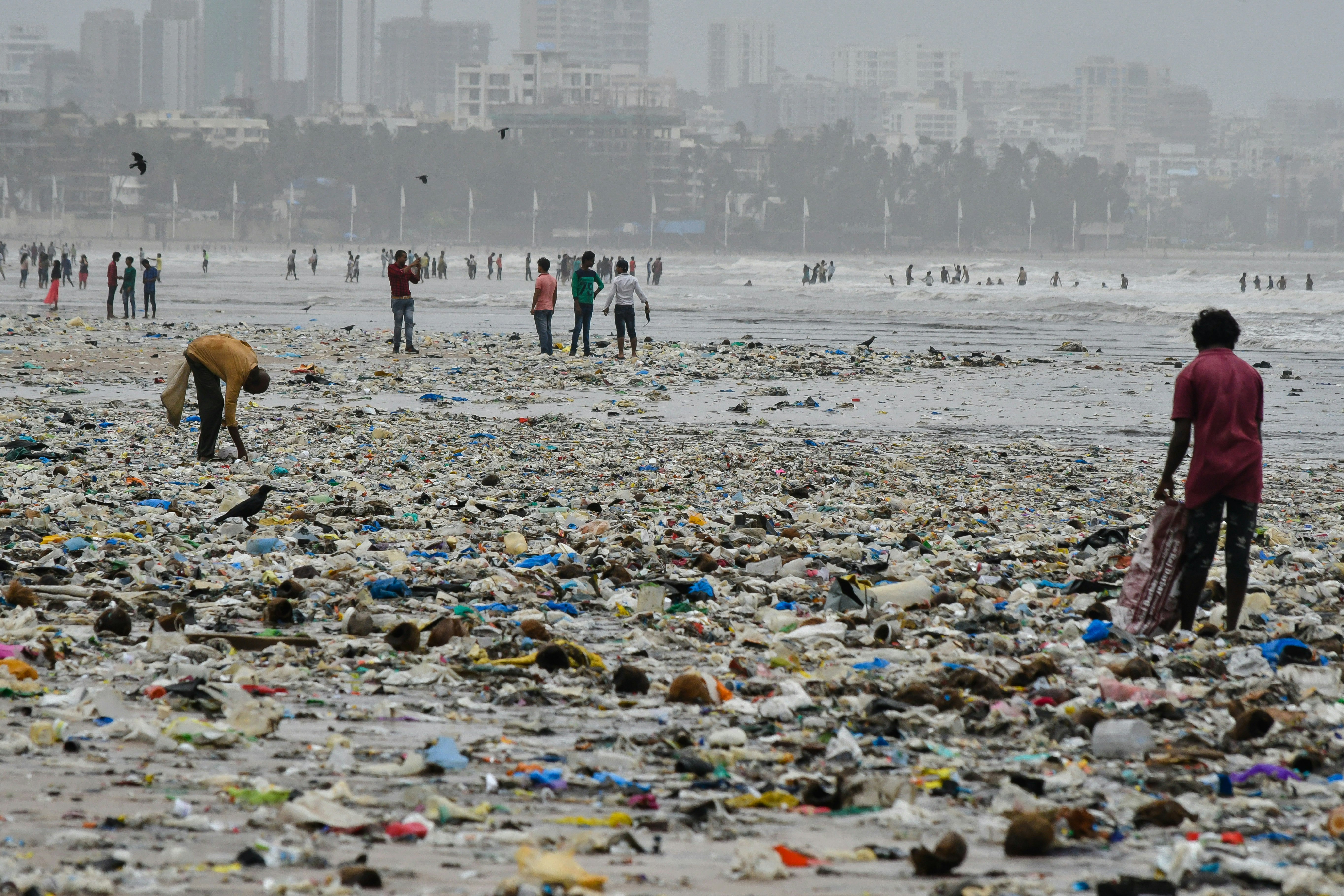 Two litter pickers work their way through the rubbish that carpets the sand of Juhu Beach in Mumbai. The beach is completely covered in litter due to the recent monsoon storms.