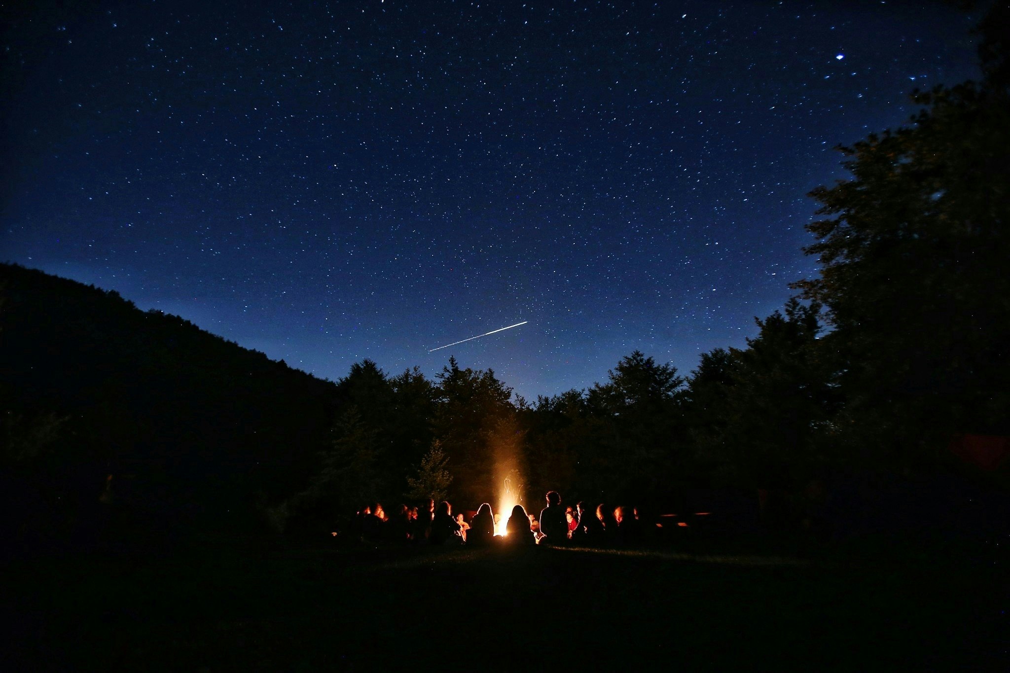 a group around a campfire under a starry sky