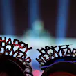 The tops of two people's heads; they're wearing novelty 'Happy New Year' headbands, and the very blurred outline of an illuminated Brandenburg Gate can be seen in the background.