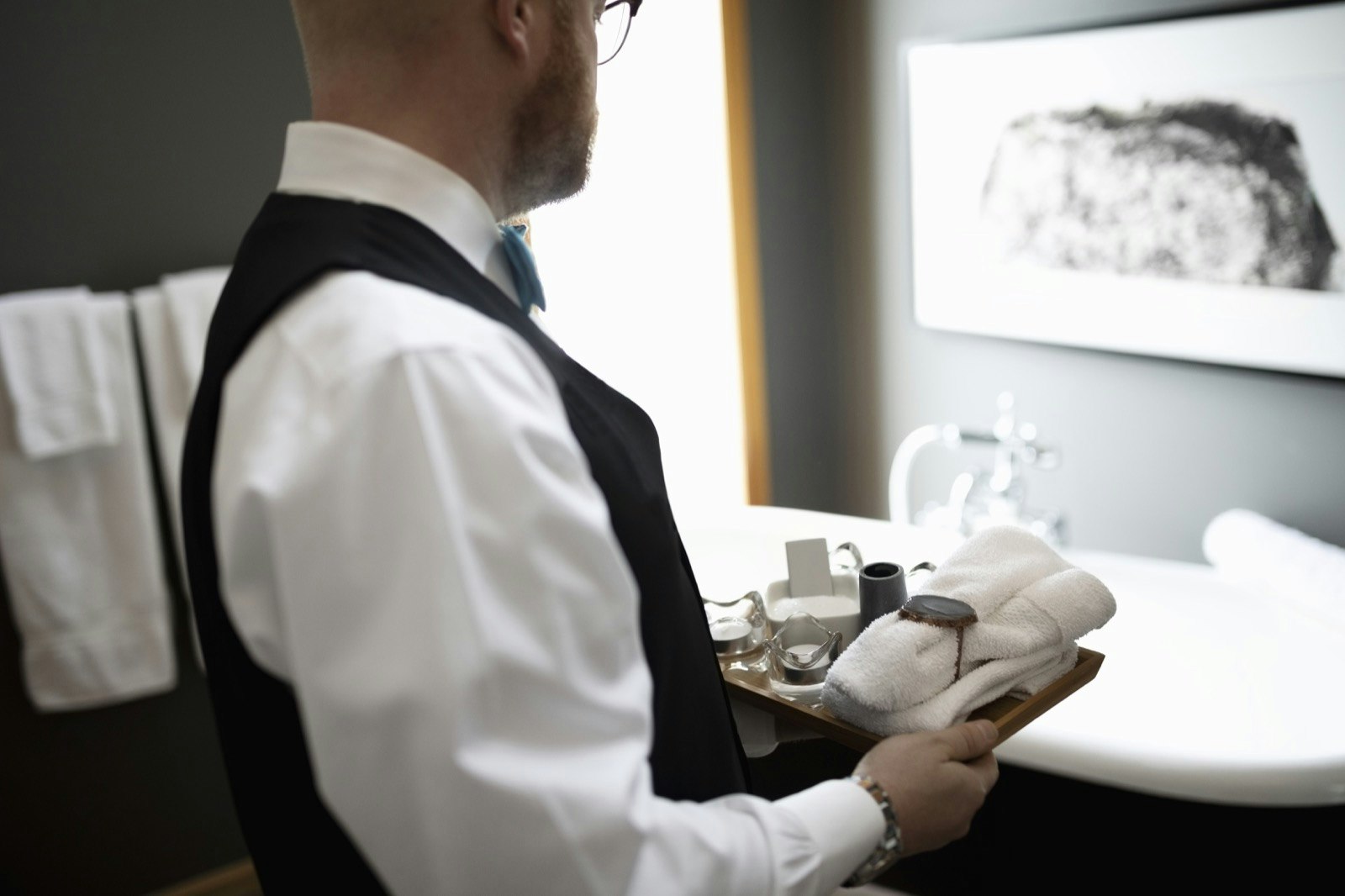 A butler prepares a bathroom for a guest.