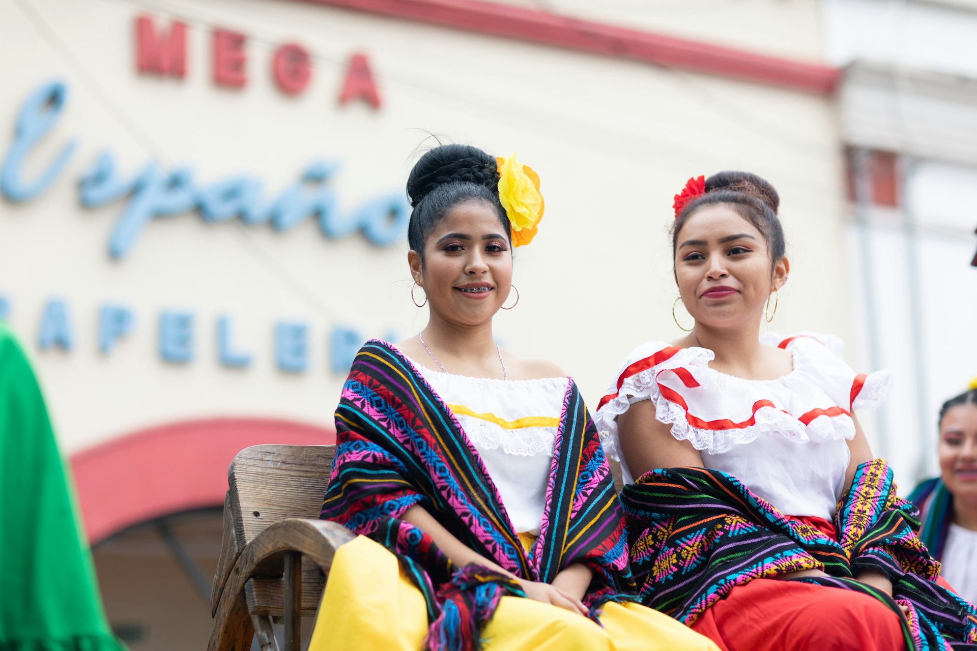 Young girls wearing traditional Mexican clothing going down the road on a float