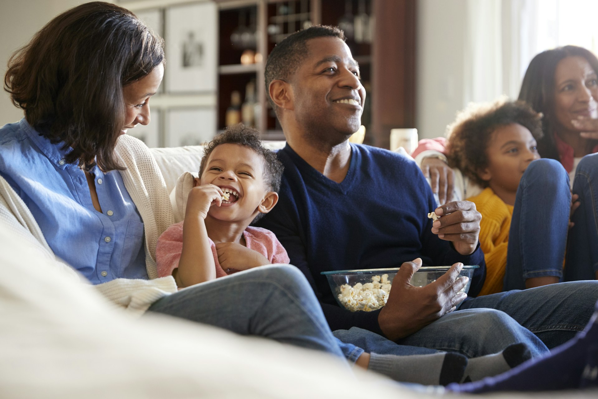 a family sits on a couch smiling and eating popcorn