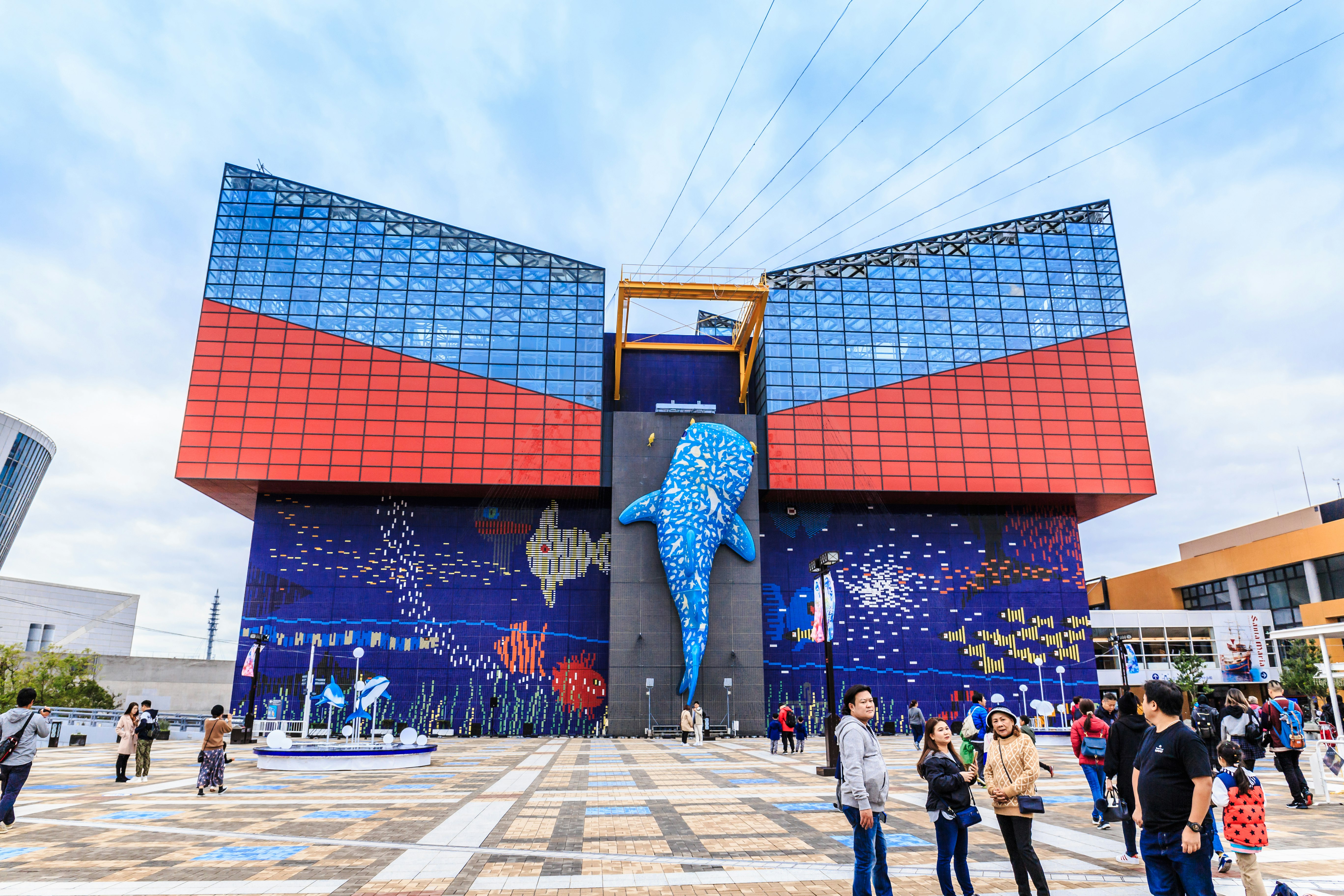 The facade of the aquarium is predominantly blue and red. There's a large fish sculpture as the centrepiece, with a mosaic of different smaller fish either side