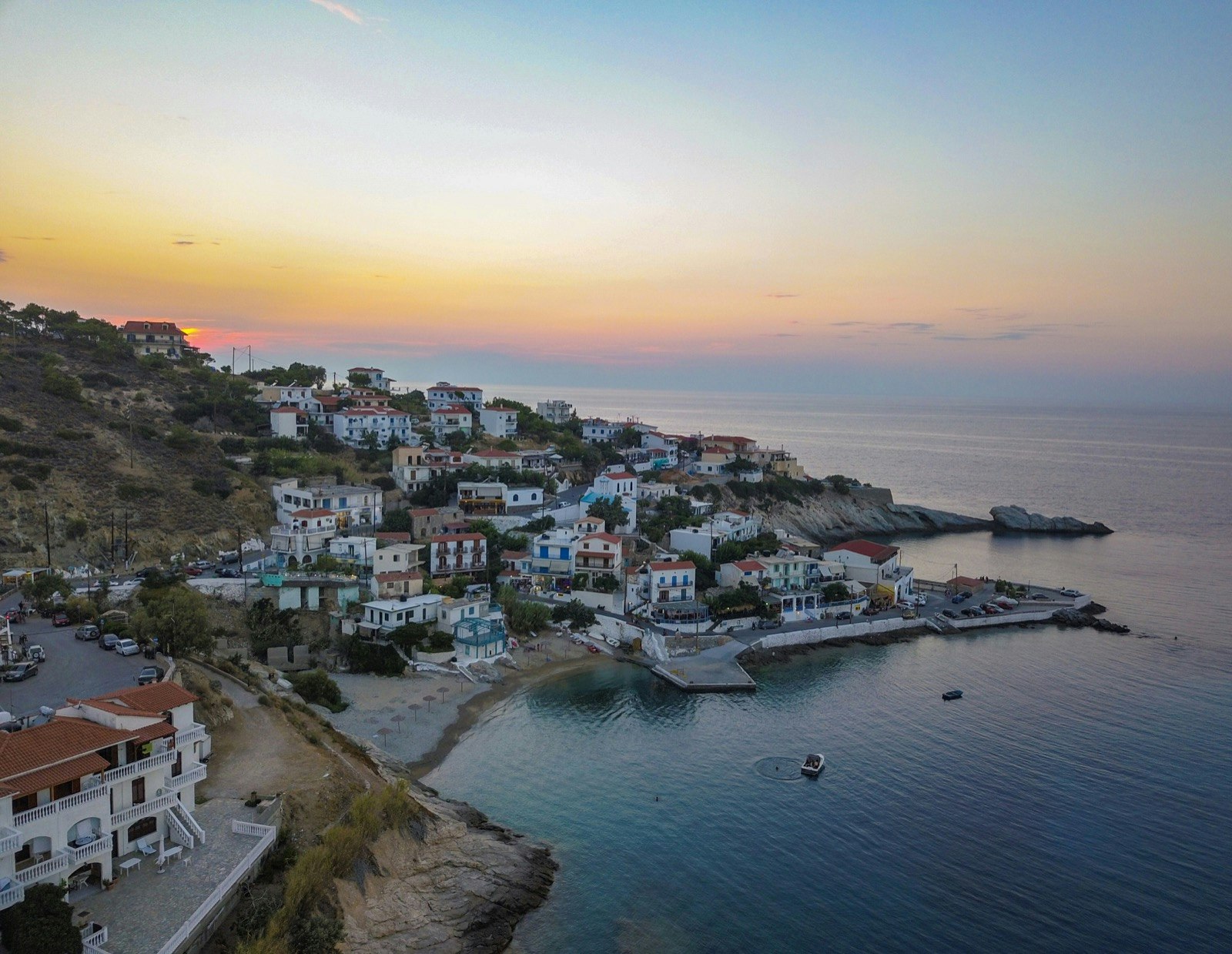 A small village rises up a mountain from a bay filled with small boats