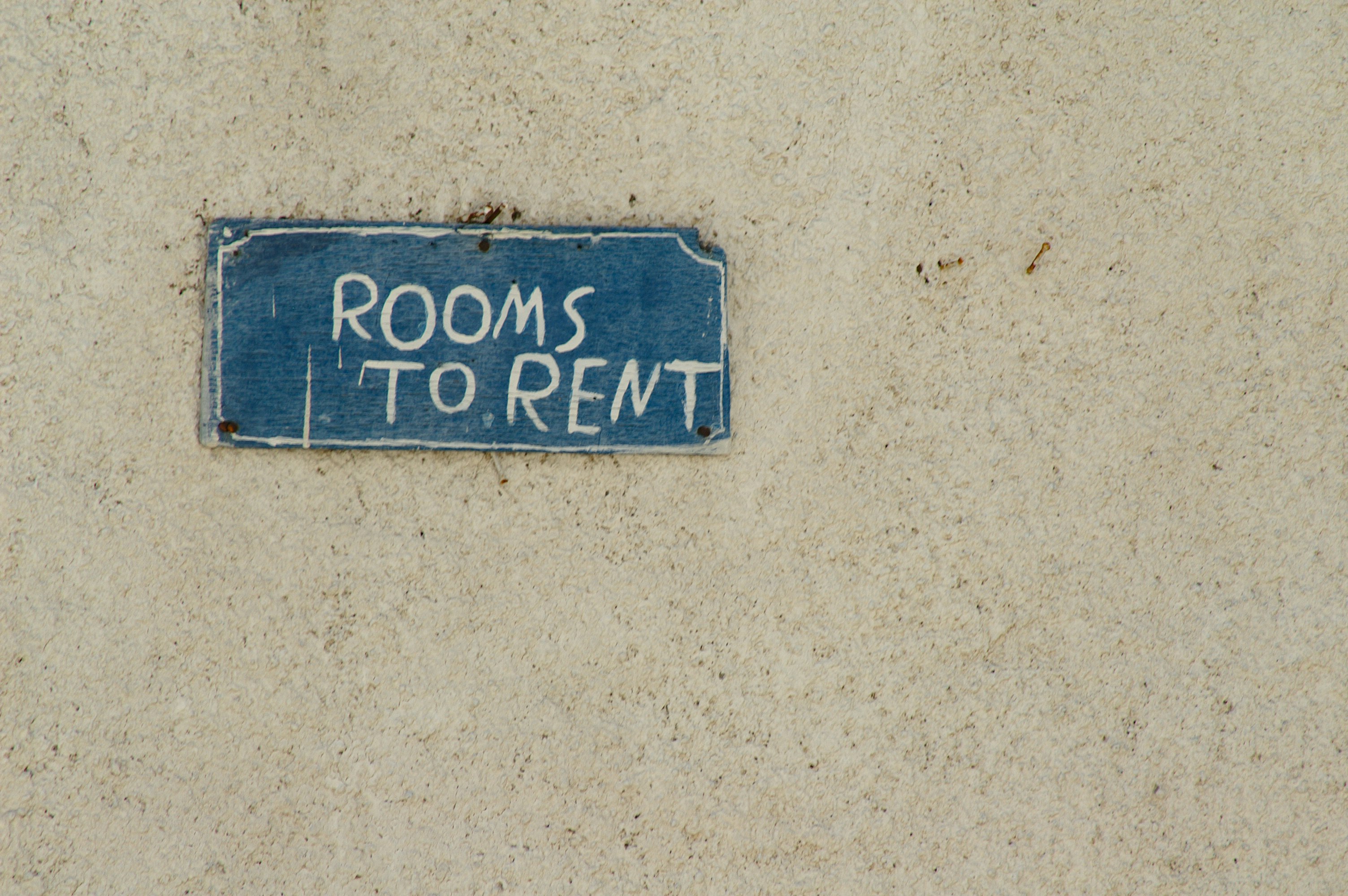 A sign that reads 'ROOMS TO RENT' hangs on a wall.