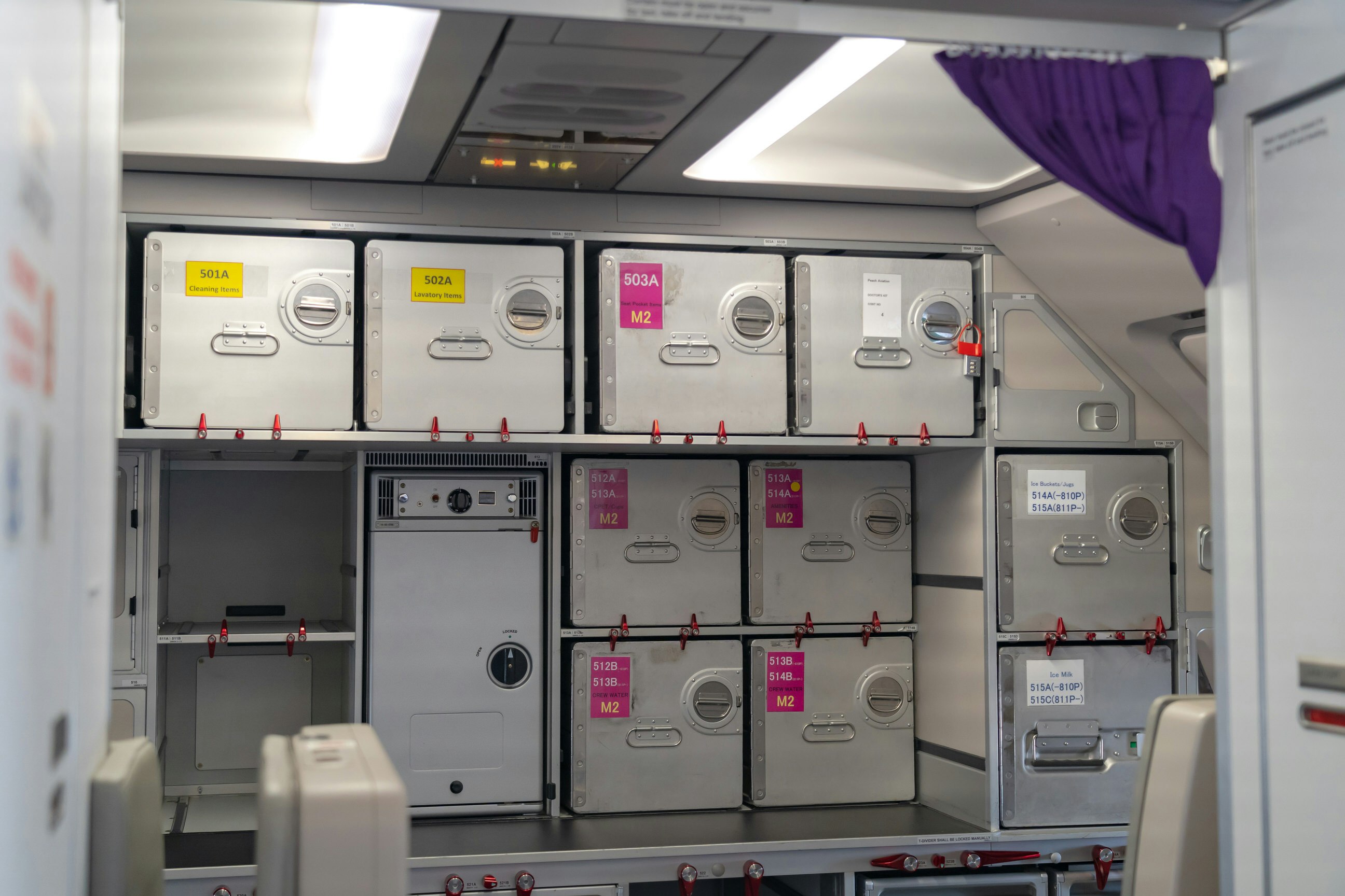 Stainless steel boxes and trolleys are neatly stowed away in special compartments in an aircraft's galley kitchen.
