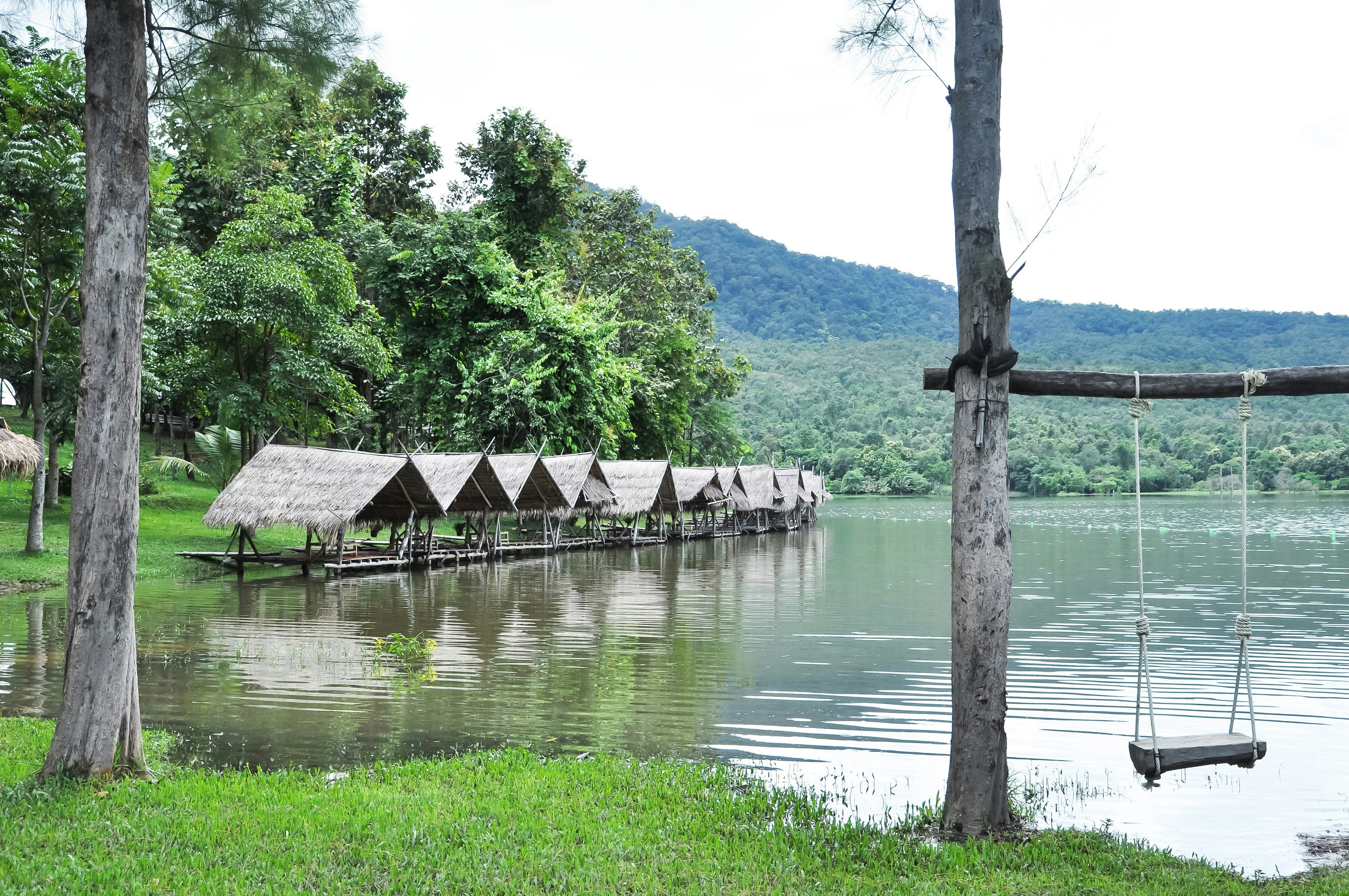 A line of bamboo huts stand at the edge of Huay Tung Tao, a man-made reservoir near Chiang Mai. A swing dangles from a tree in the foreground.