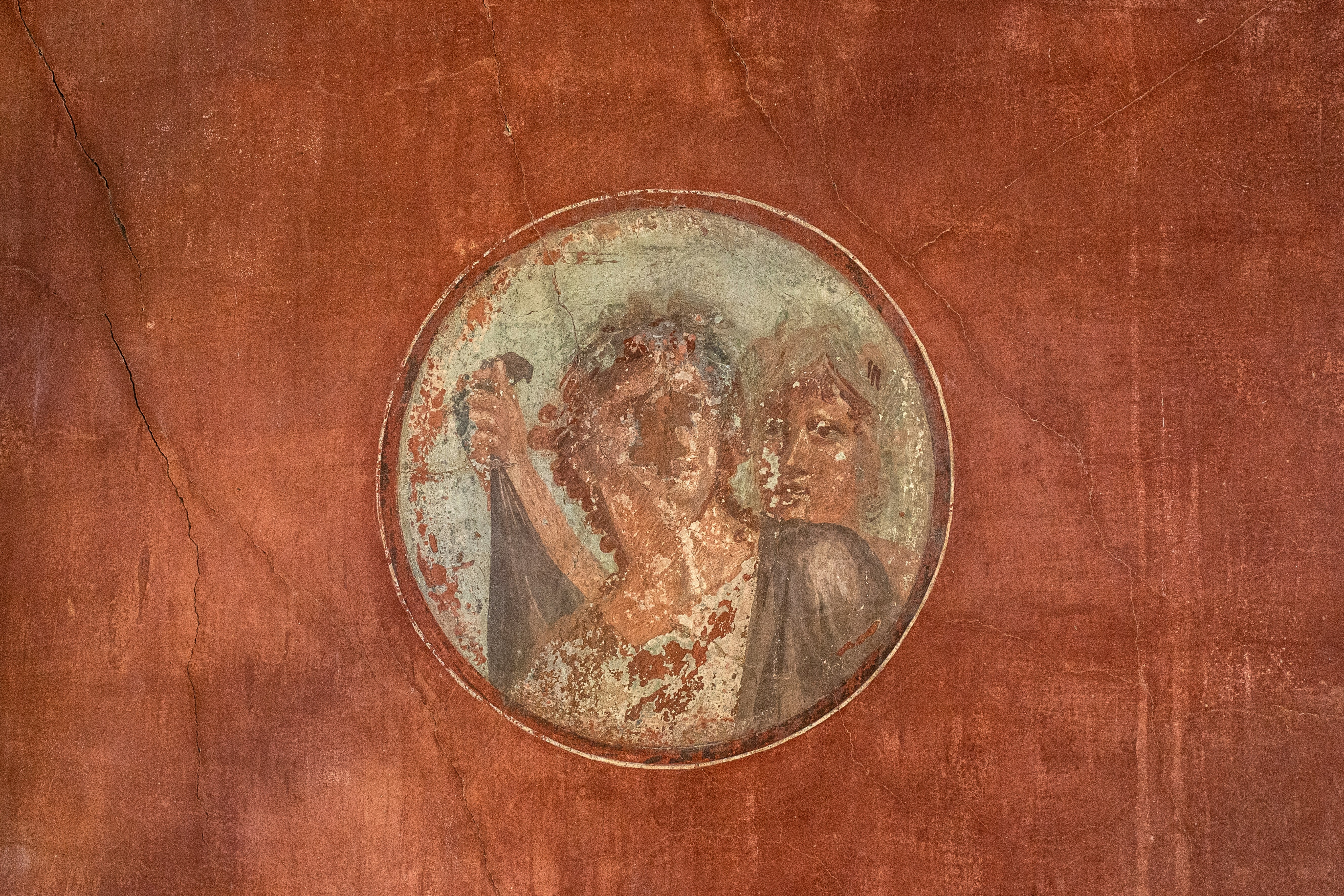Ancient Roman fresco depicts the face of a man against a clay wall