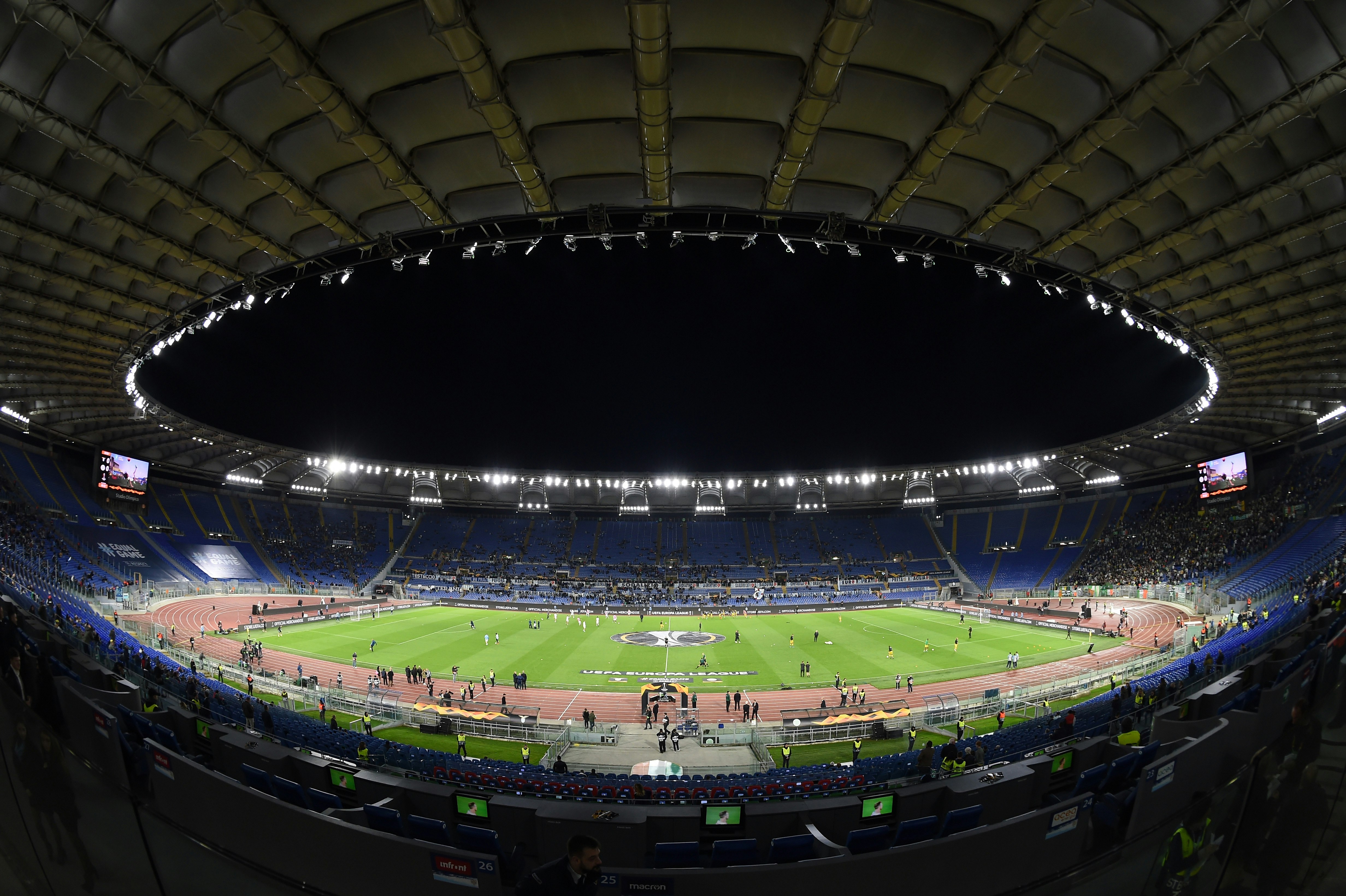 A fish-eye view of the inside of Rome's Stadio Olympico; the football pitch is floodlit and there is a game underway 