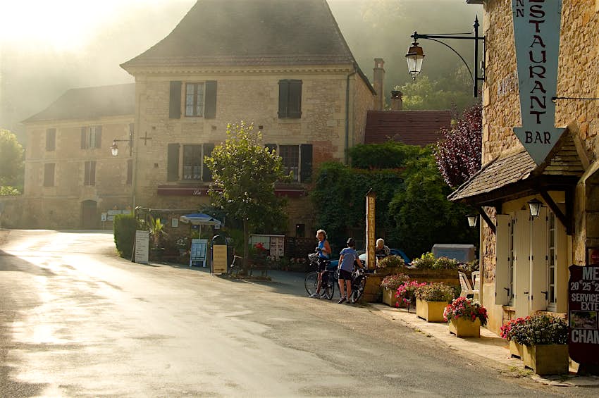 1000 Cafes France Three women park their bikes outside outside a small village French cafe on a bright morning