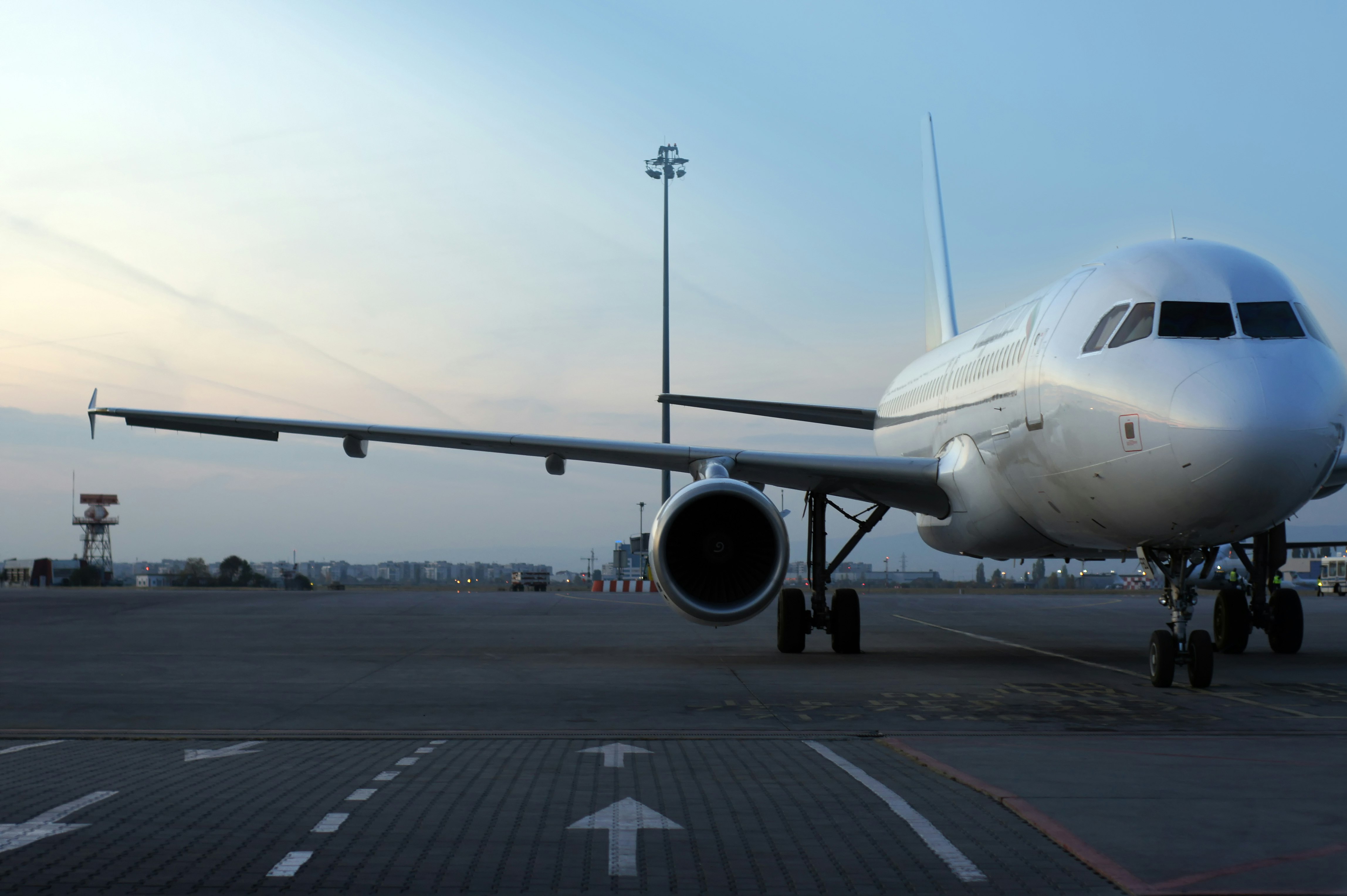 A commercial plane on the tarmac at an aiport at dusk