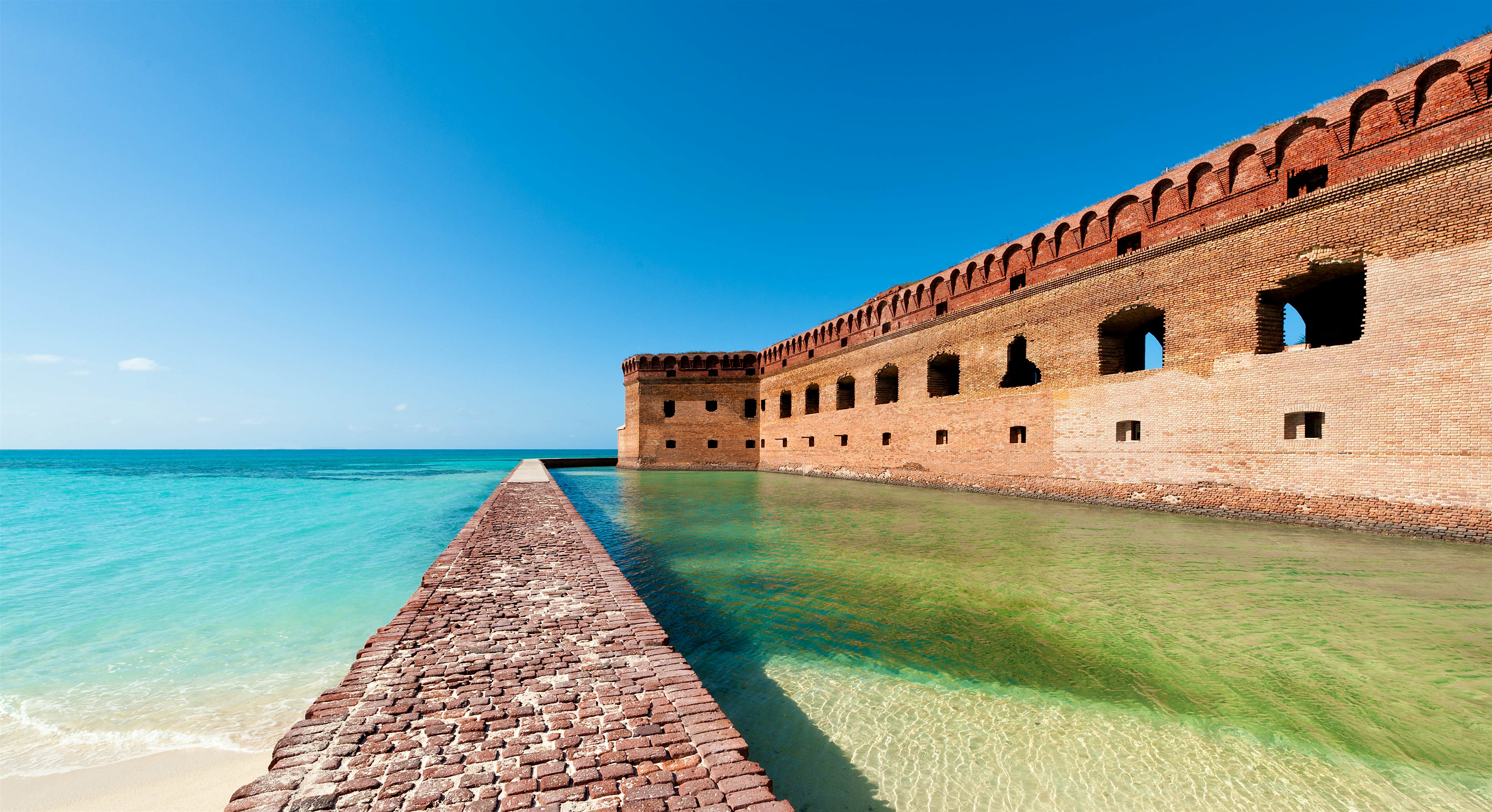 Dry Tortugas National Park A brick walkway and the imposing Fort Jefferson, contrasting against crystal-clear water in Dry Tortugas National Park near Key West, Florida