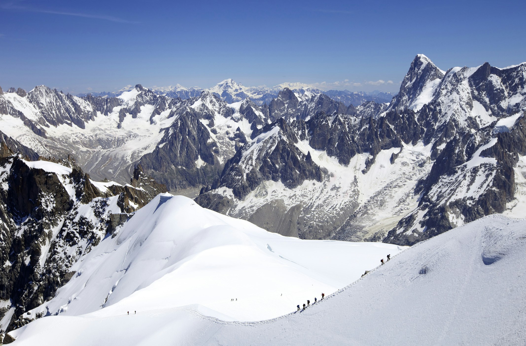 Team of mountaineers hike across a snowcapped mountain 