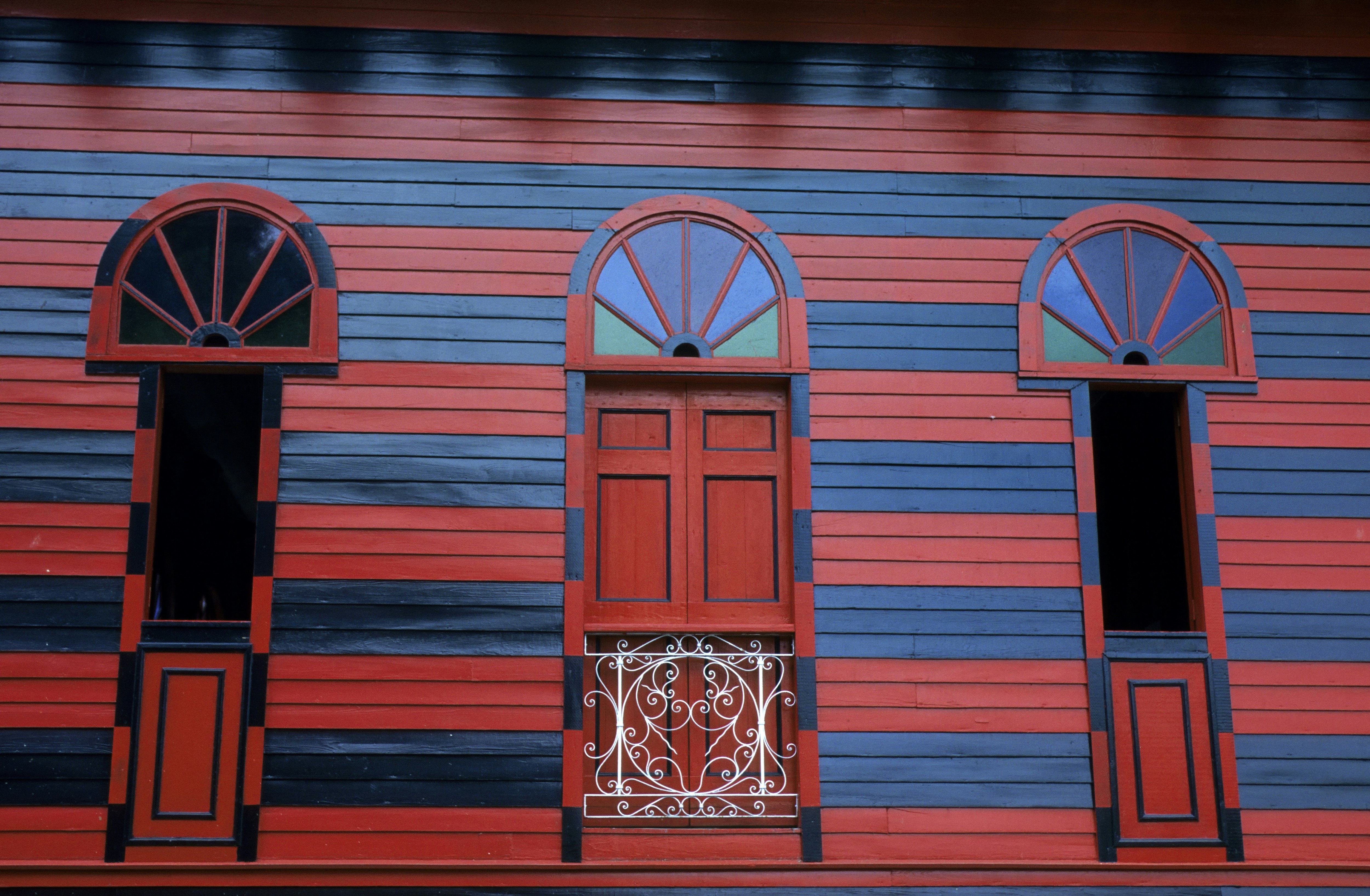 Close-up of a red-and-navy striped building facade with fan-shaped ornamental windows in Ponce, Puerto Rico