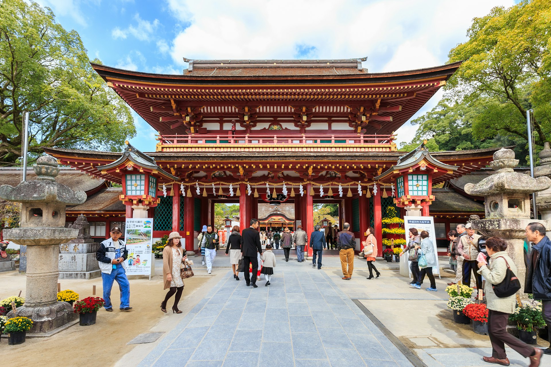 Many visitors walking through the huge, red, decorative entrance to Dazaifu Tenman-gū.