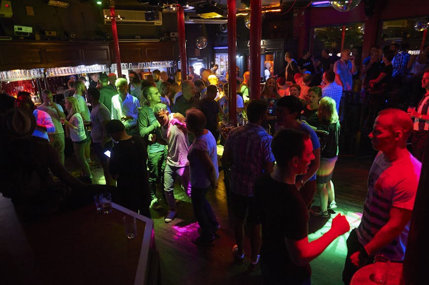 A packed dancefloor at the Royal Vauxhall Tavern; beyond is a bar lined with red columns.