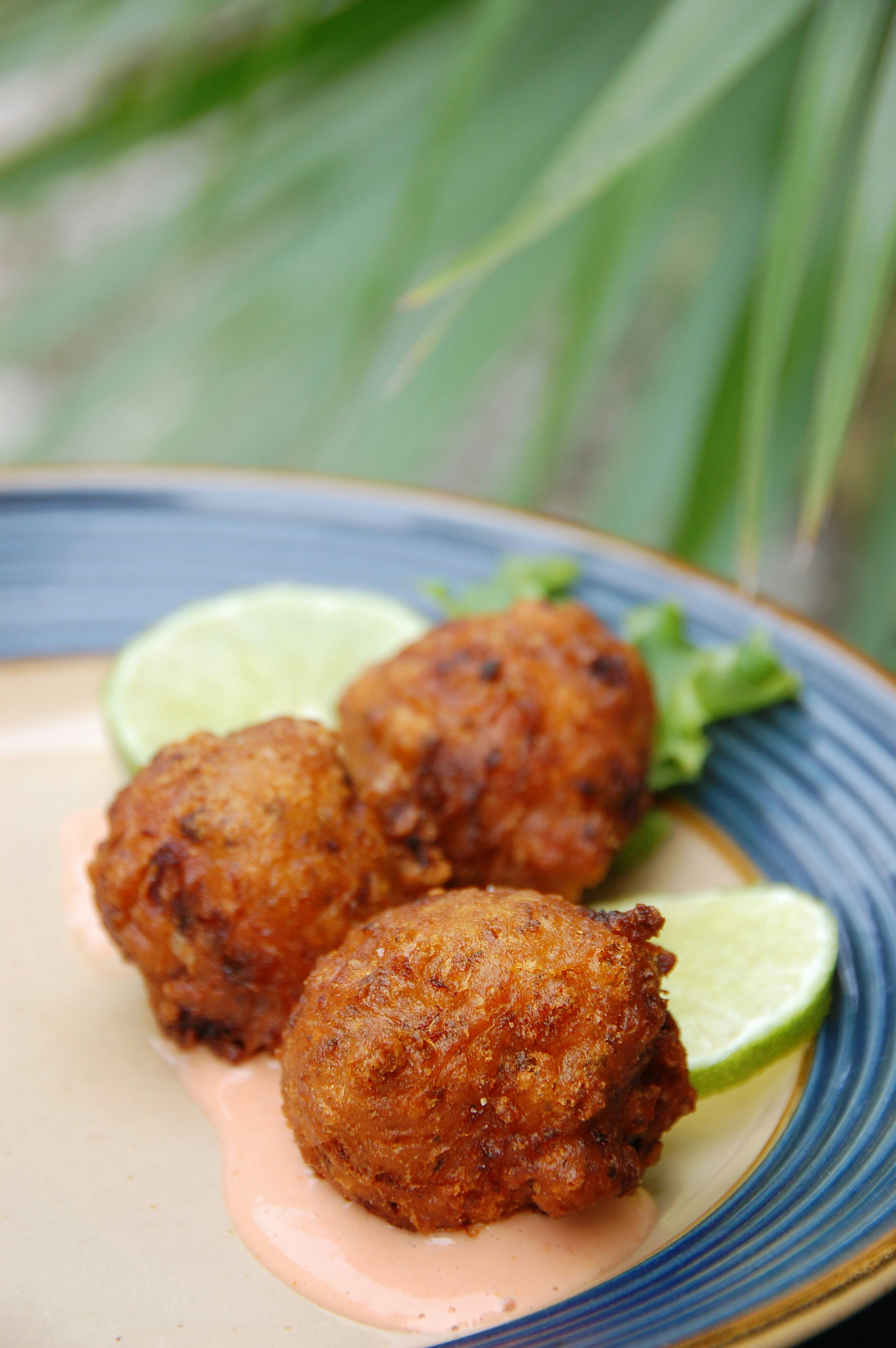 Tre friterade konchfritter, en specialitet från Florida Keys, serverad med lime och dippsås.