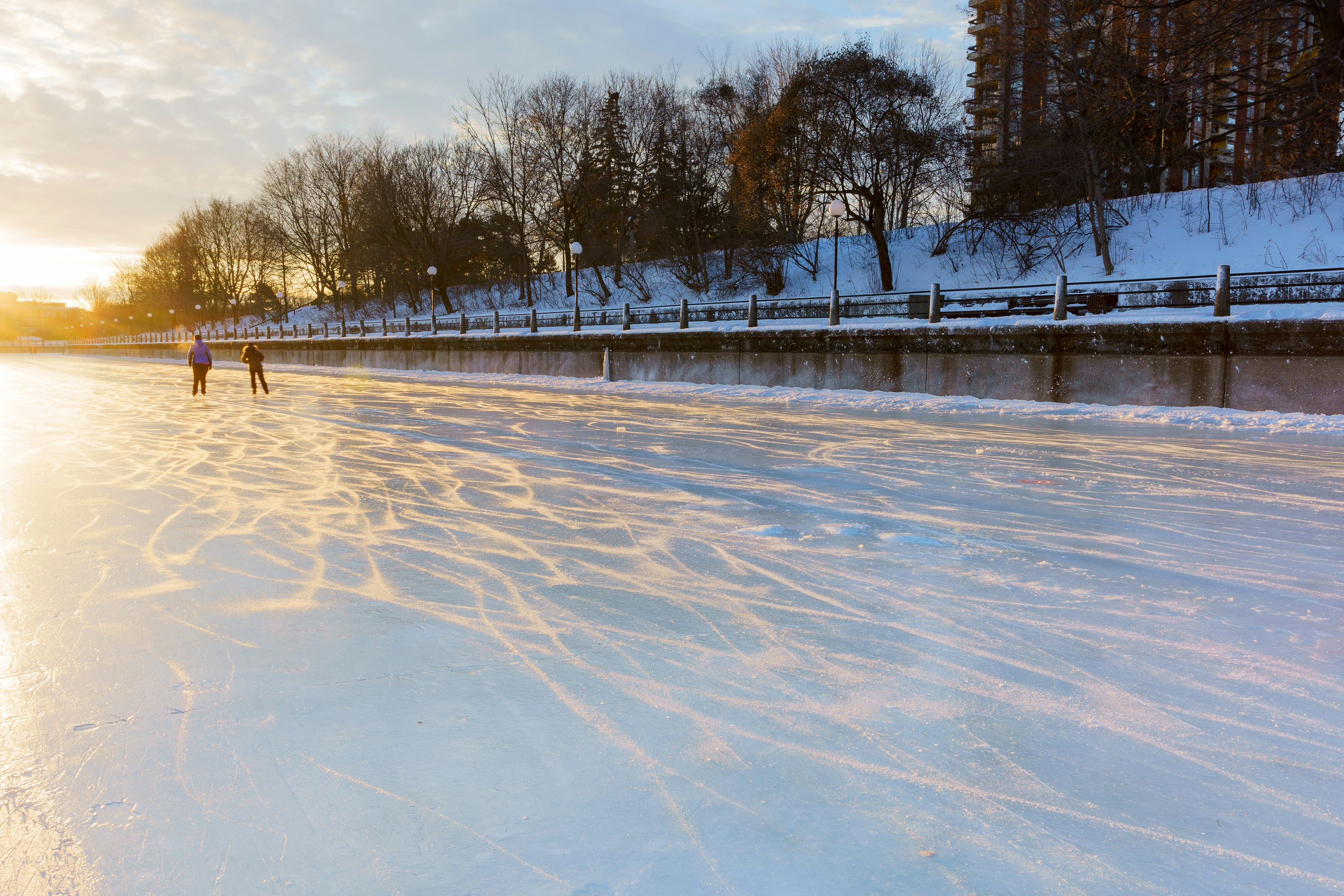 two people skate on a frozen river during sunrise