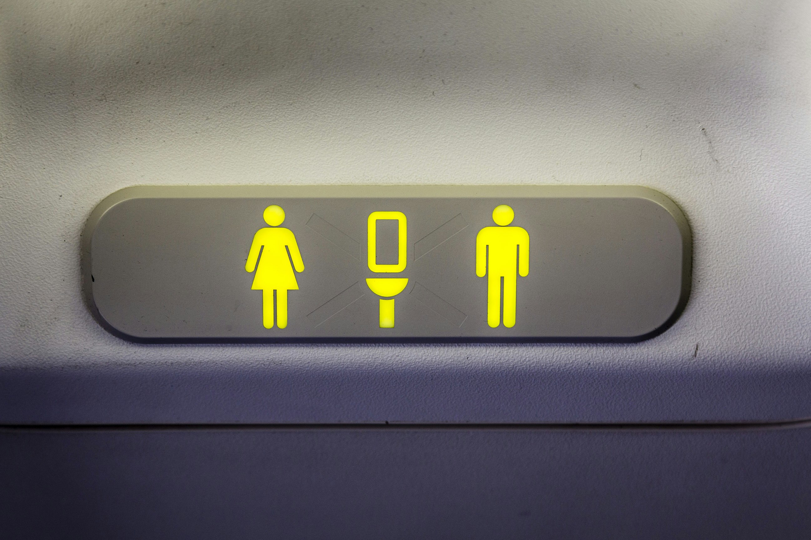 A close-up of a lavatory sign, indicating that the aircraft toilet is unoccupied, with yellow symbols for a man and a woman.