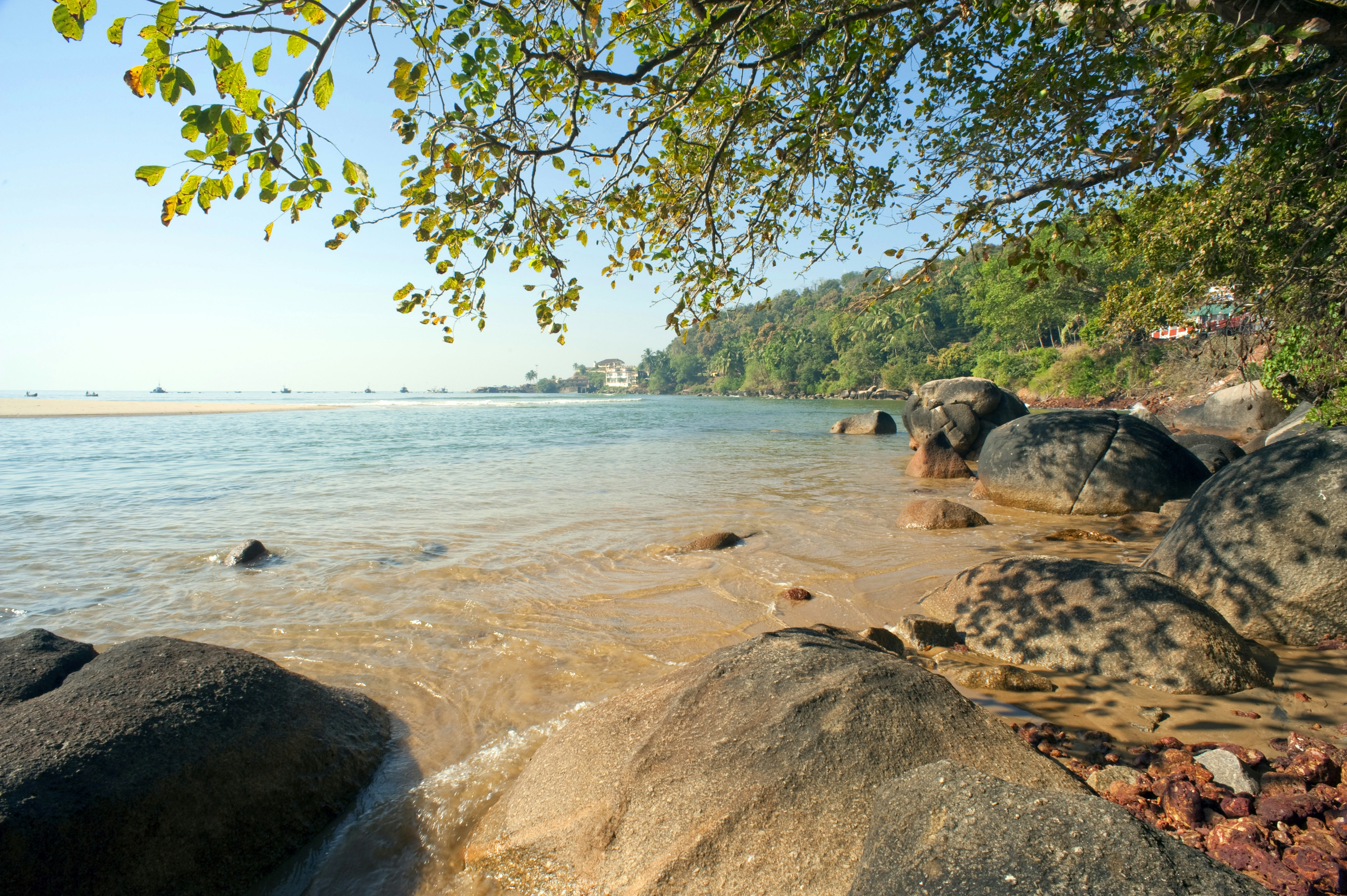 The boulder-strewn coastline of Vengurla, with beautiful blue waters backed by a forested coastline