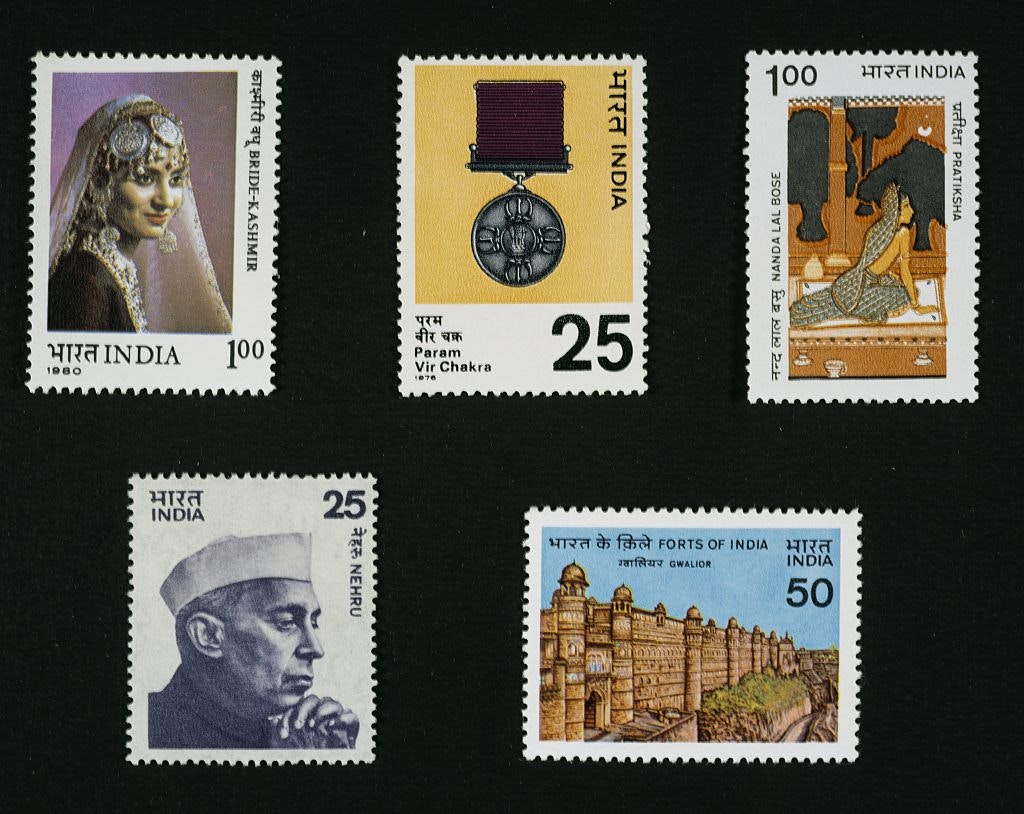 Five vintage Indian postage stamps are mounted on a black background.