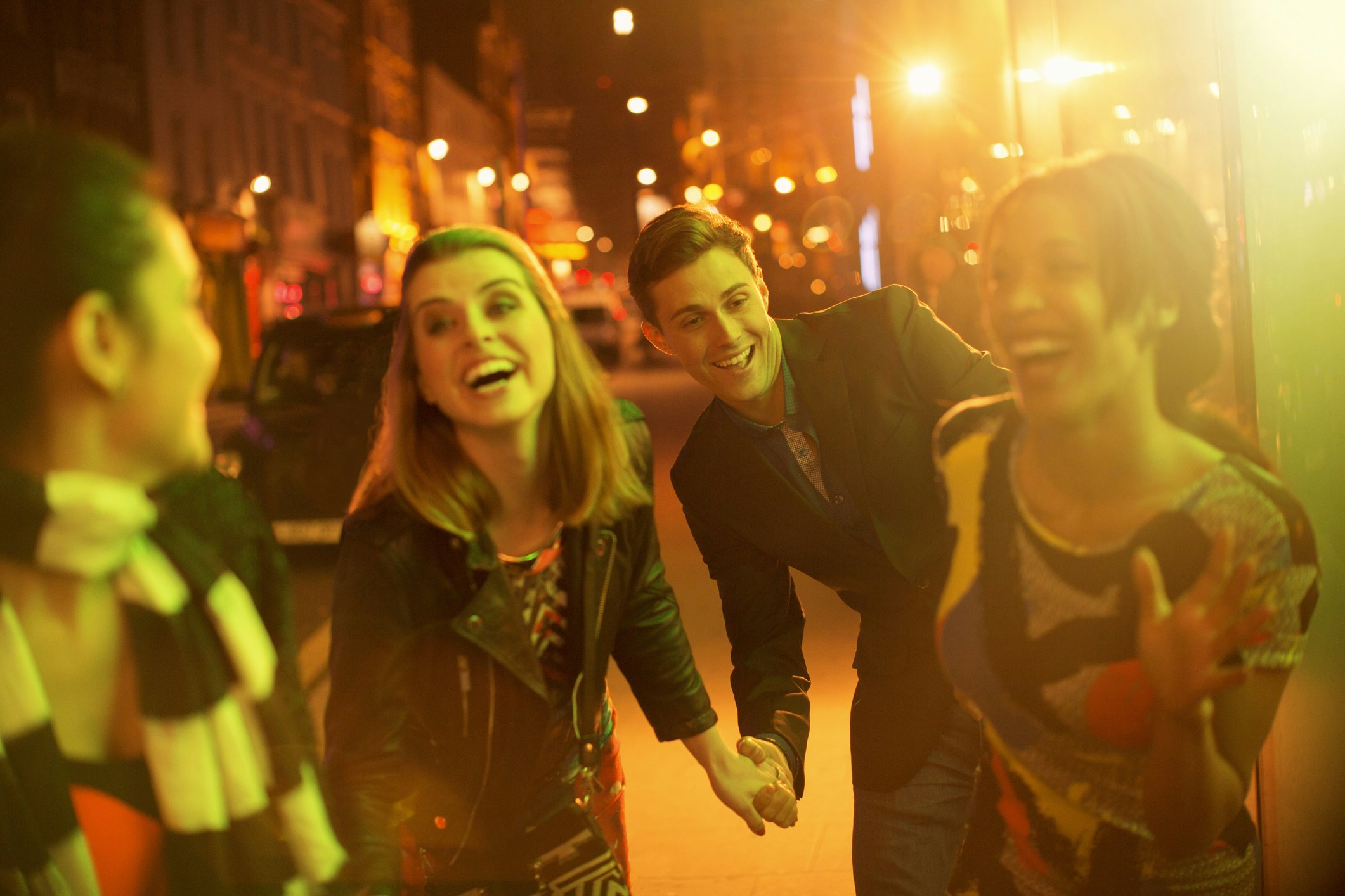 Friends walking down city street together at night 