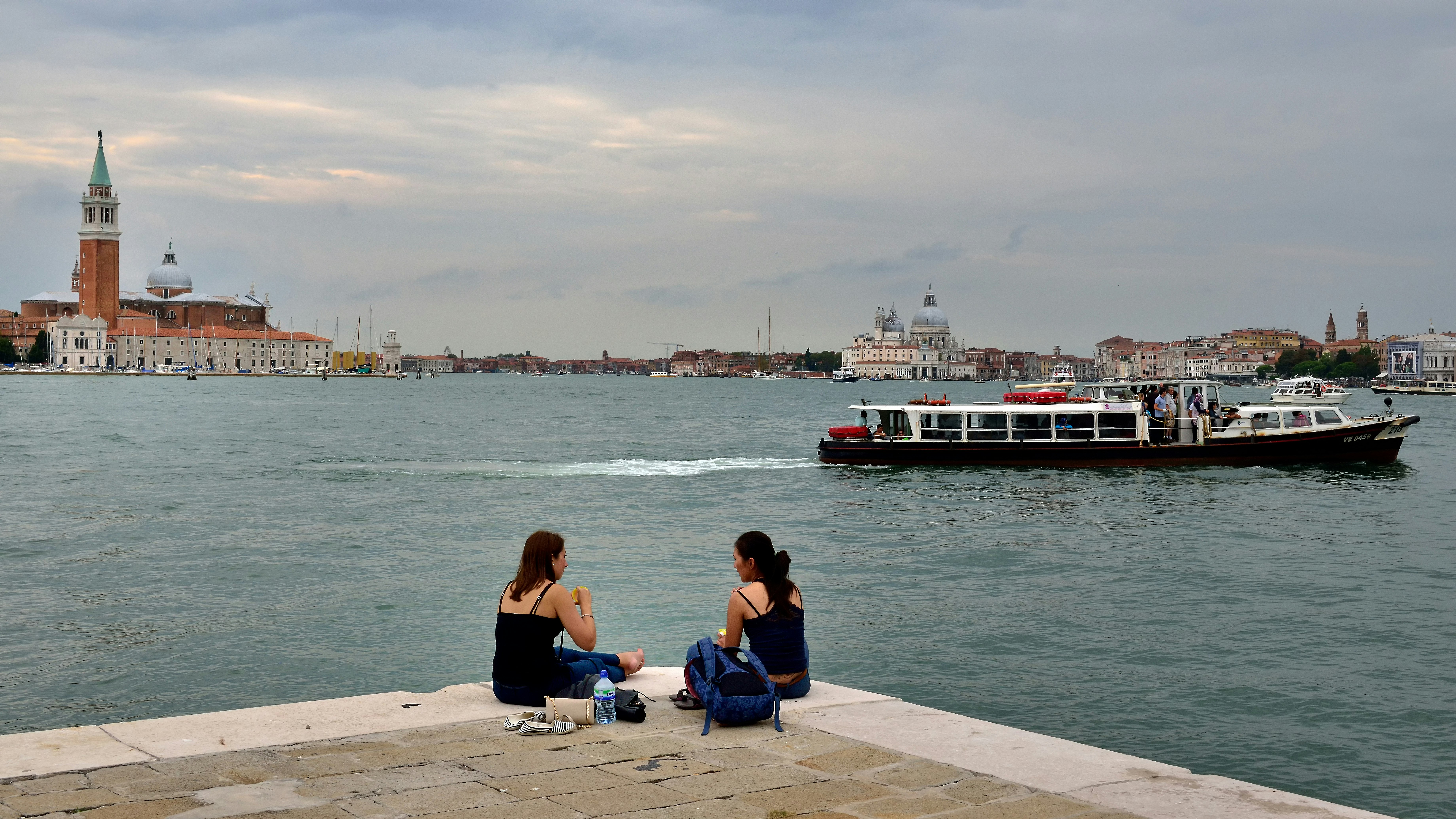 Two women have lunch next to a canal in Venice