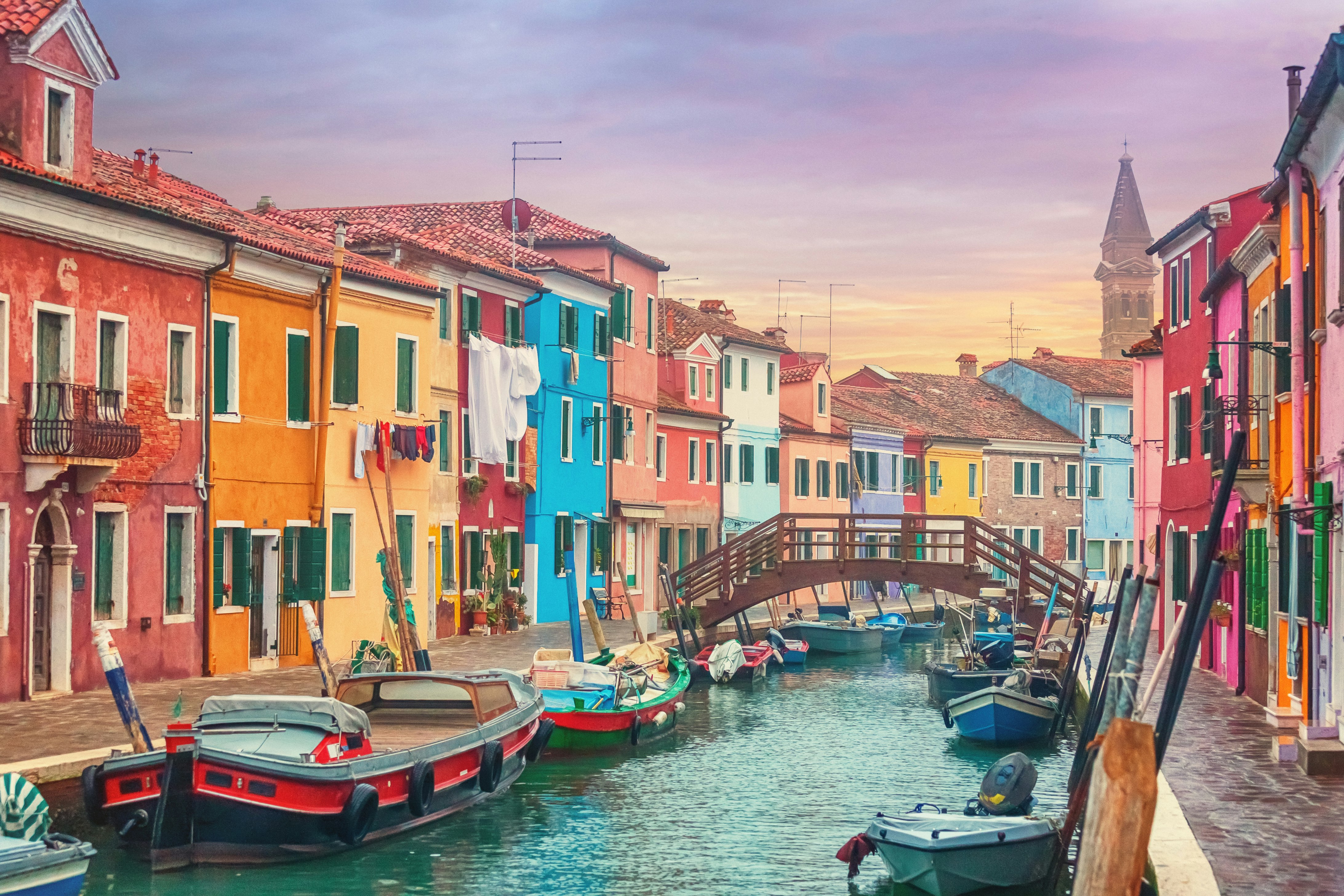 Houses painted striking primary colours along each side of a canal in Burano